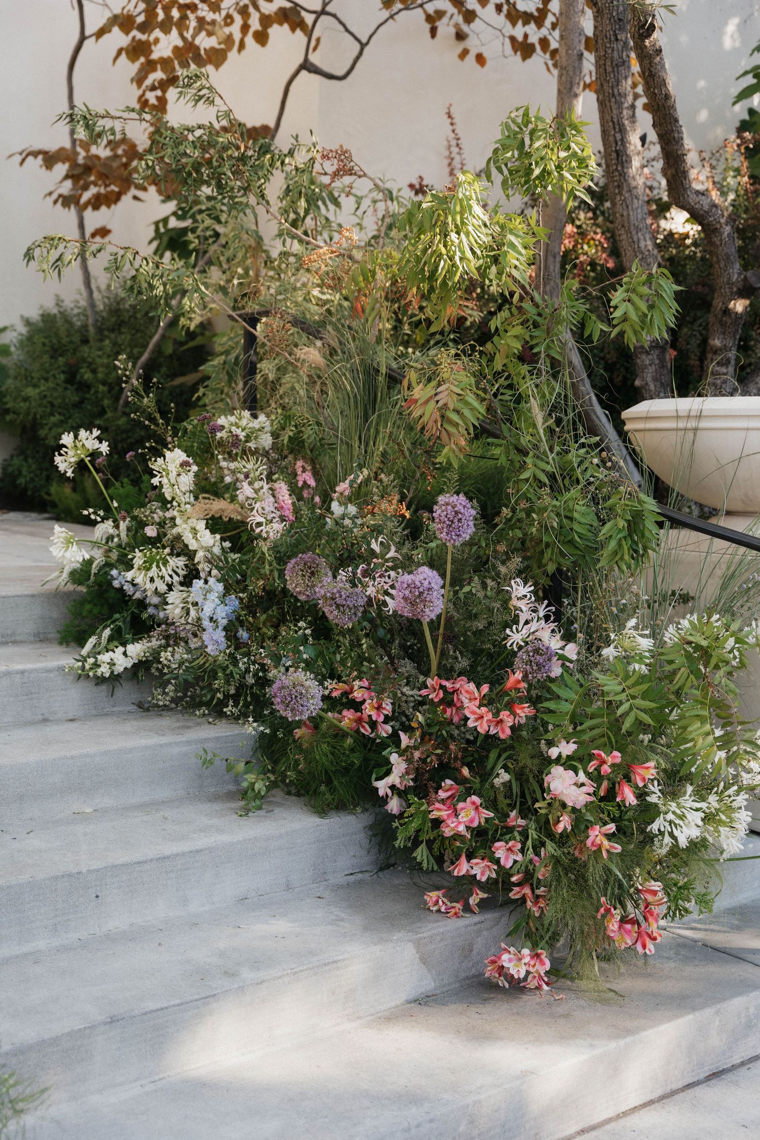 Elegant floral arrangements line concrete steps creating a romantic garden atmosphere.