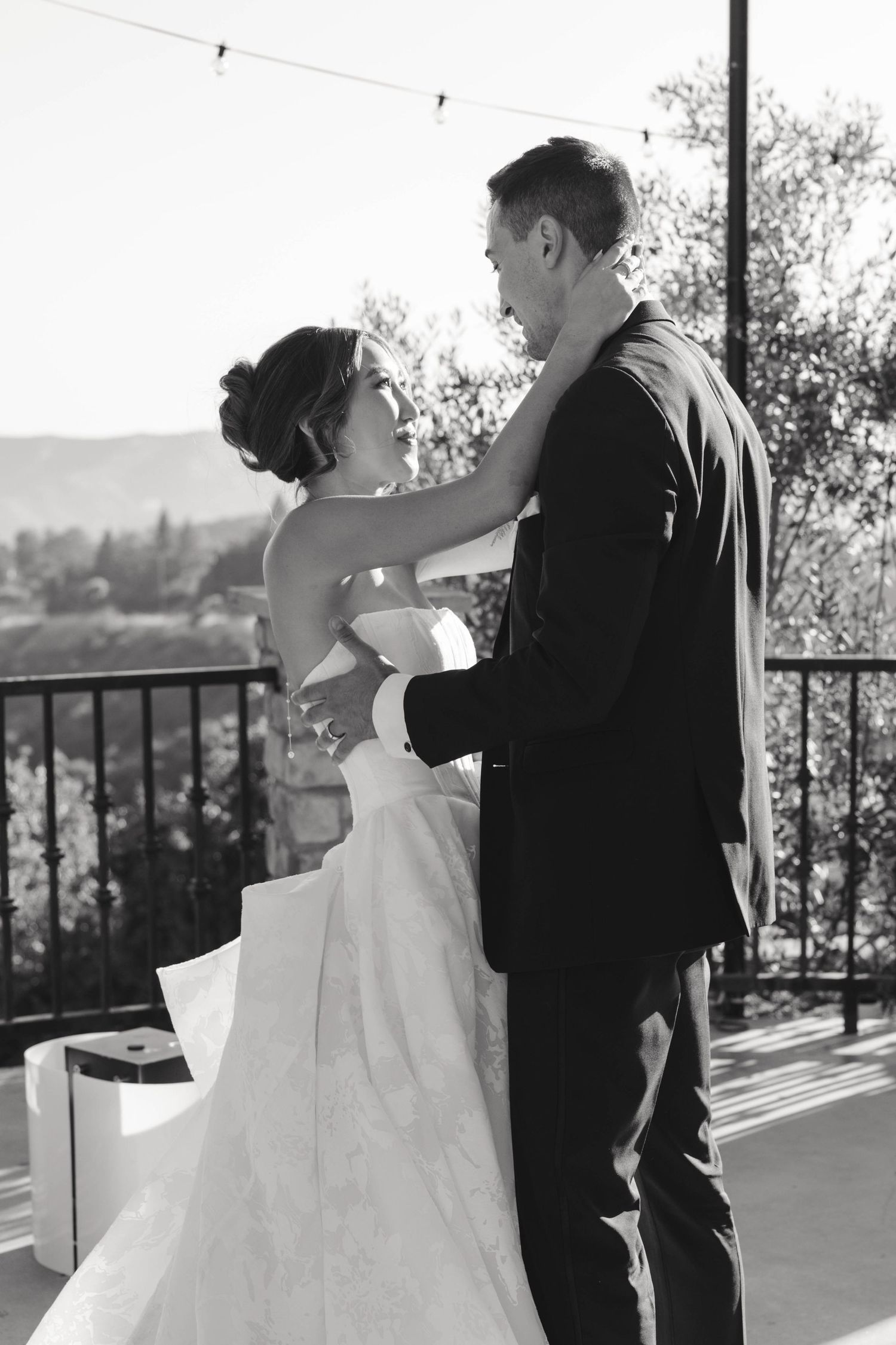 Black and white portrait of wedding couple embracing on outdoor balcony.