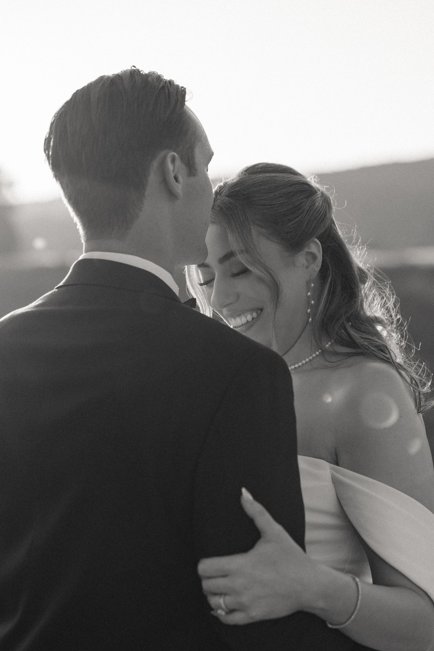 A romantic black and white moment between newlyweds in soft sunlight.