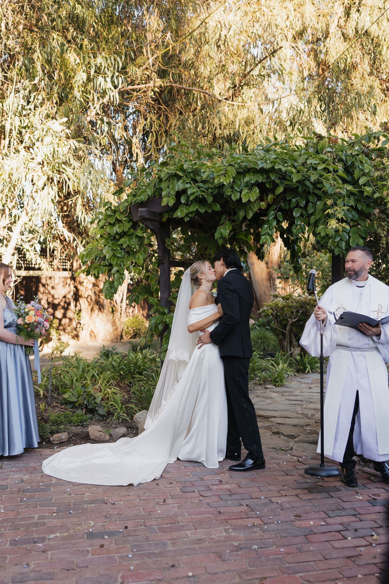 Wedding ceremony moments captured on a brick patio under weeping willow trees.