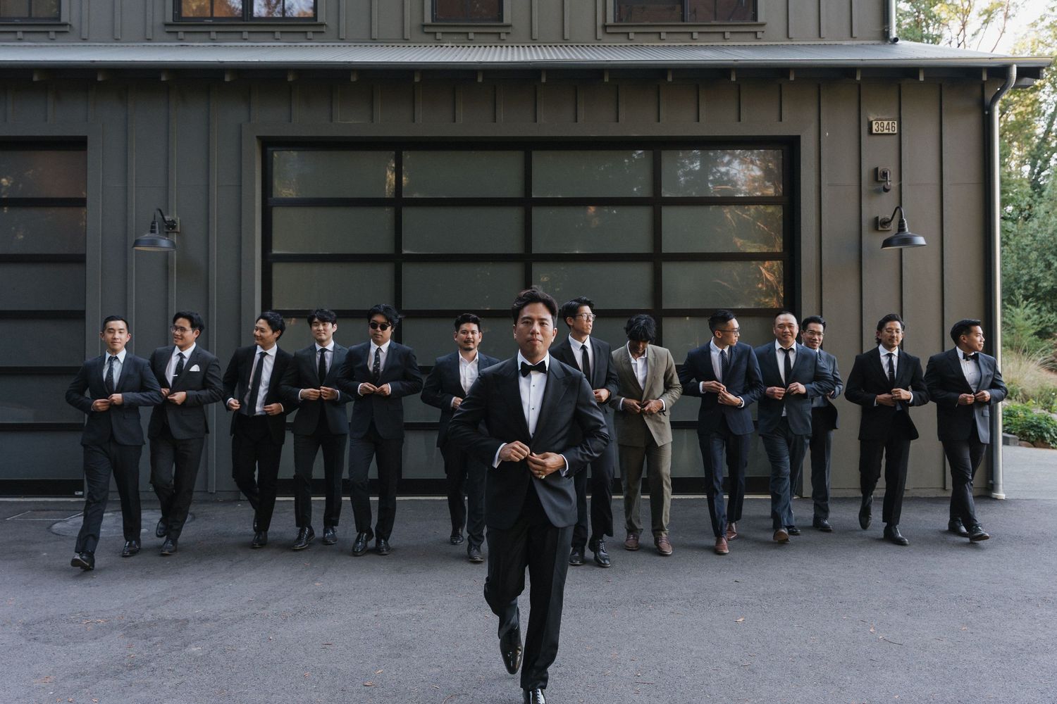 A row of formally dressed people pose in front of a dark gray building exterior.