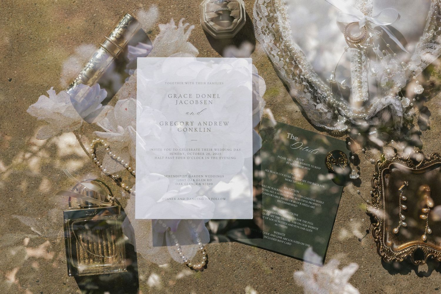 Wedding details arranged on rustic surface including rings, invitations, and decorative elements in natural lighting.