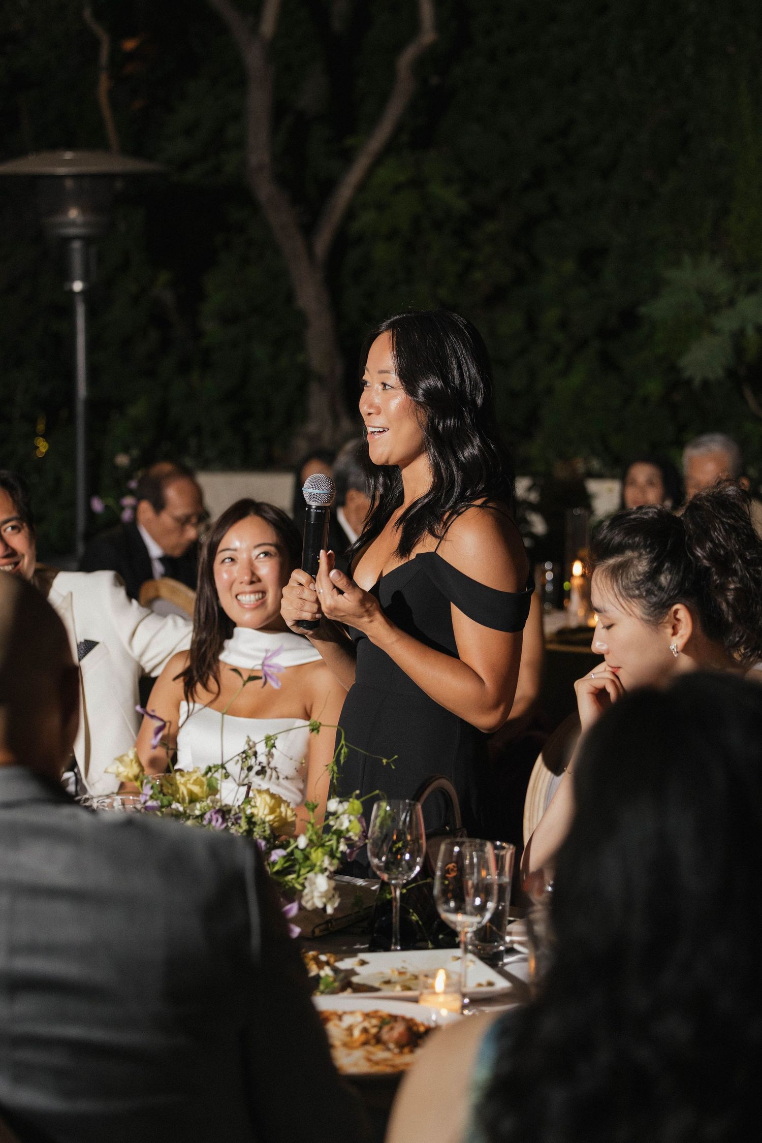 Wedding guests enjoy dinner and conversation at an outdoor evening reception.