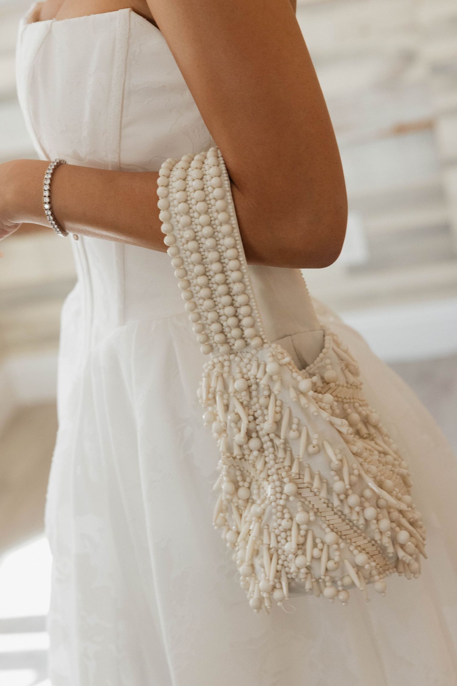 Elegant pearl-beaded bridal purse against a white wedding dress.