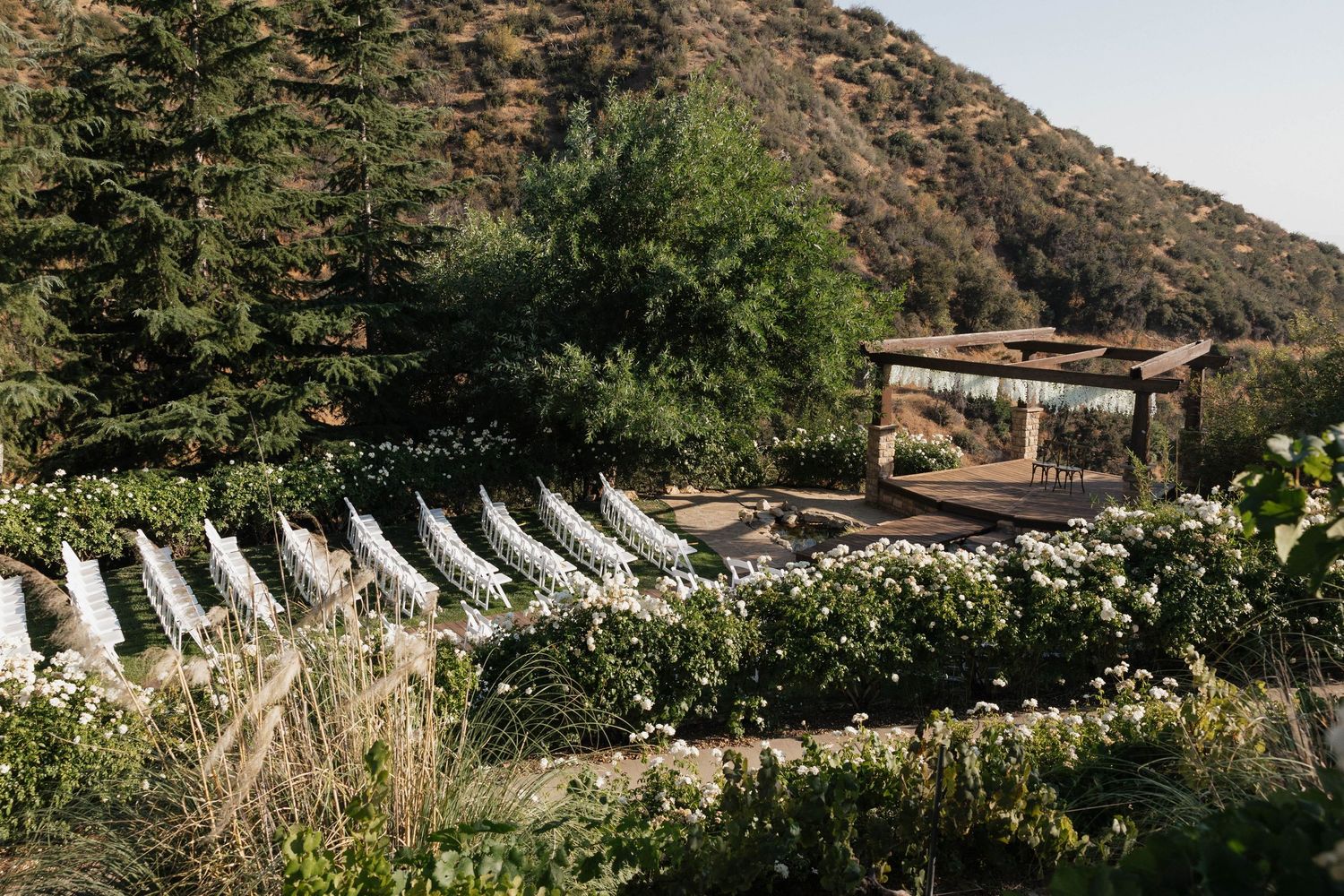 Outdoor ceremony setup with white chairs against mountain backdrop.