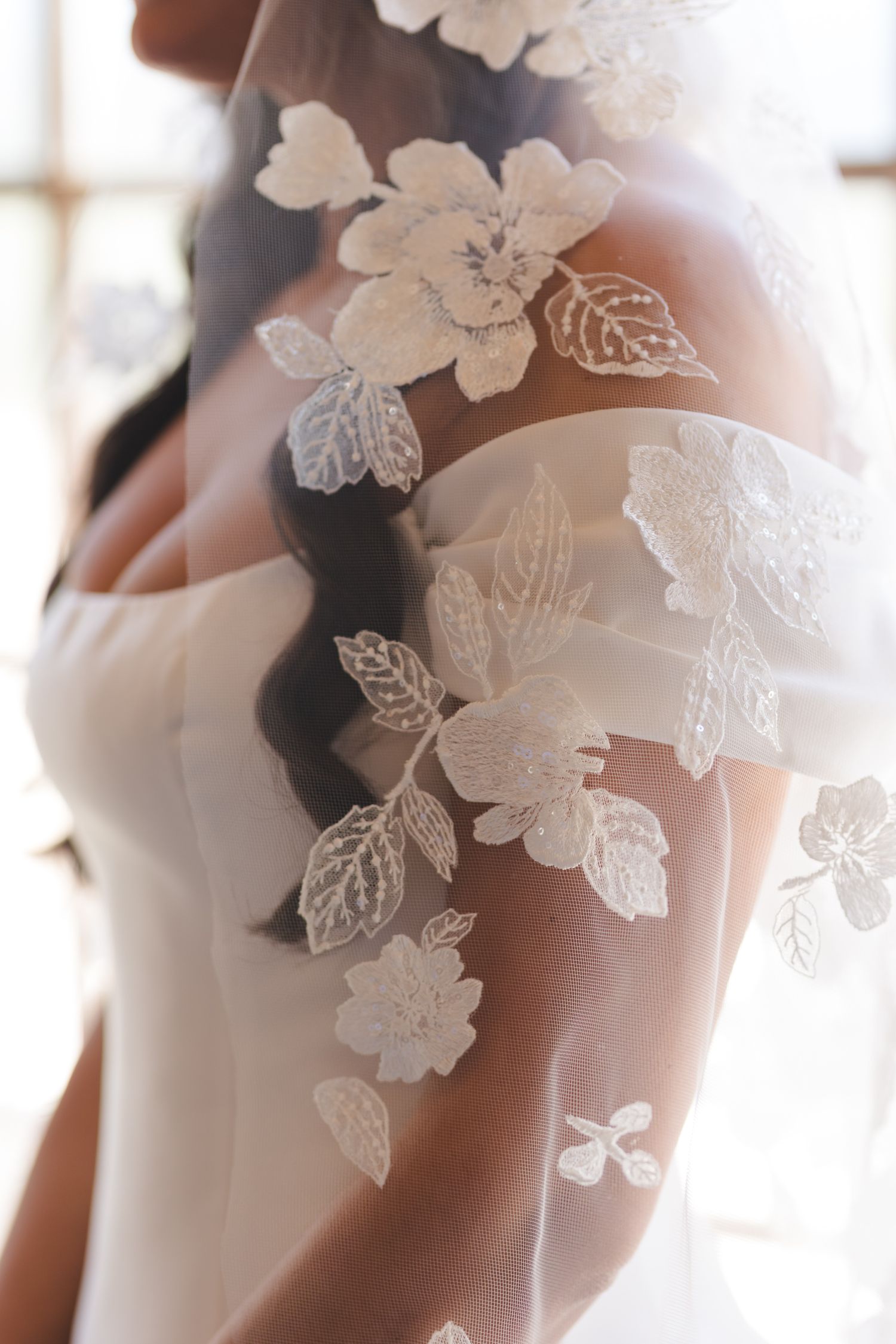 Delicate white lace butterfly appliques on wedding dress fabric.