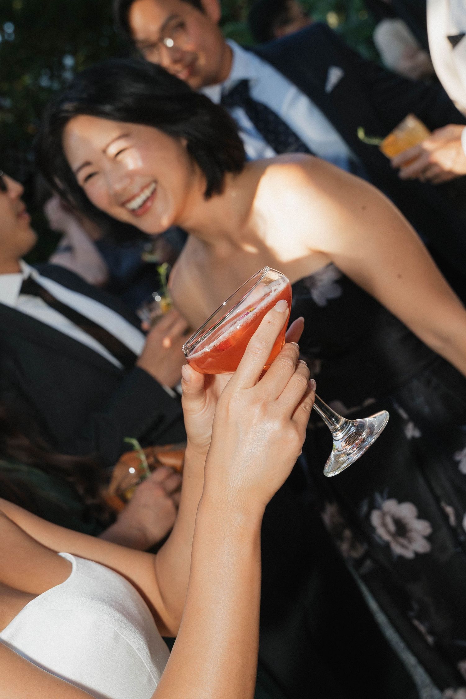 Wedding guests enjoying drinks and laughter at an evening reception.