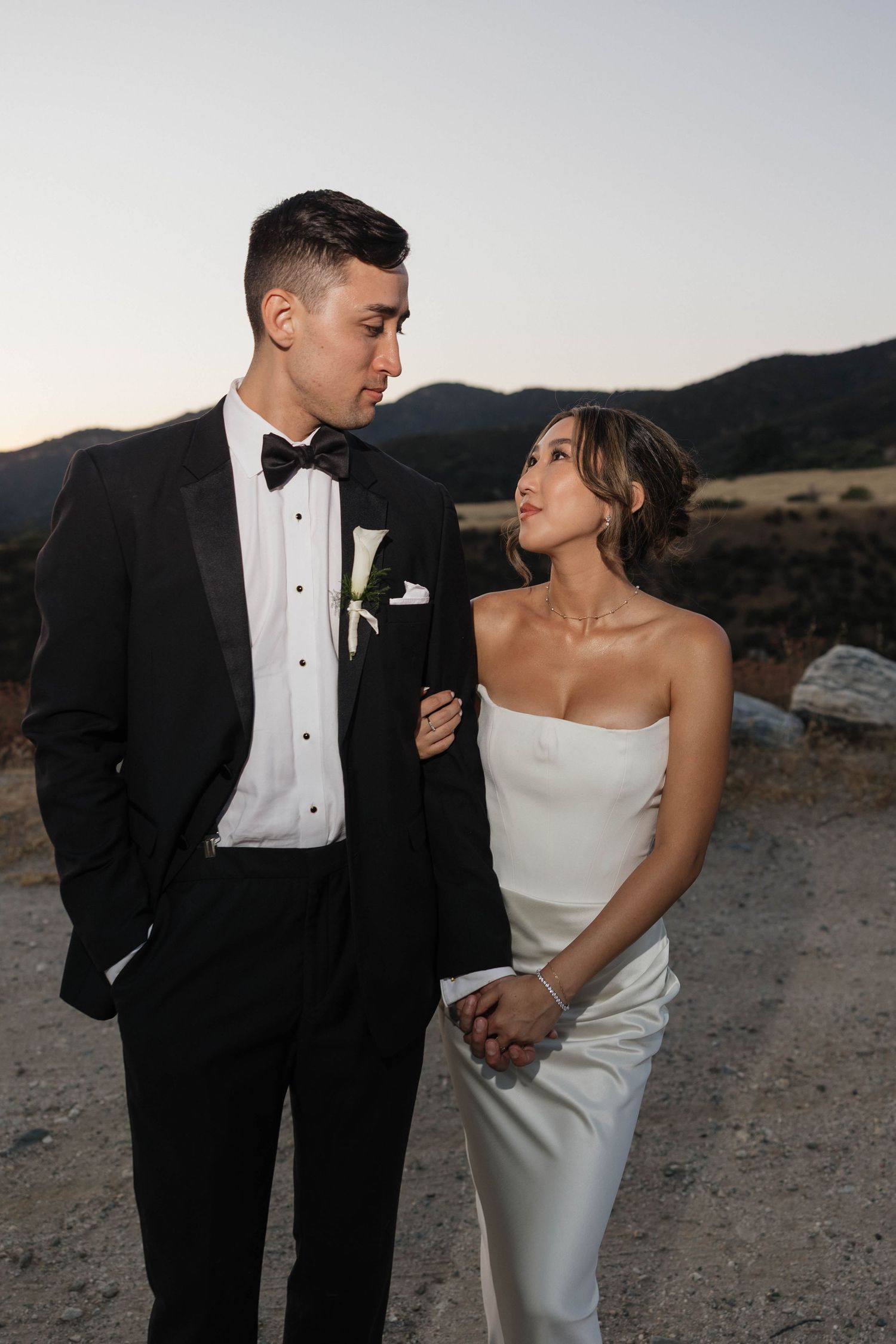 Sunset wedding portraits with dramatic mountain backdrop and formal attire.