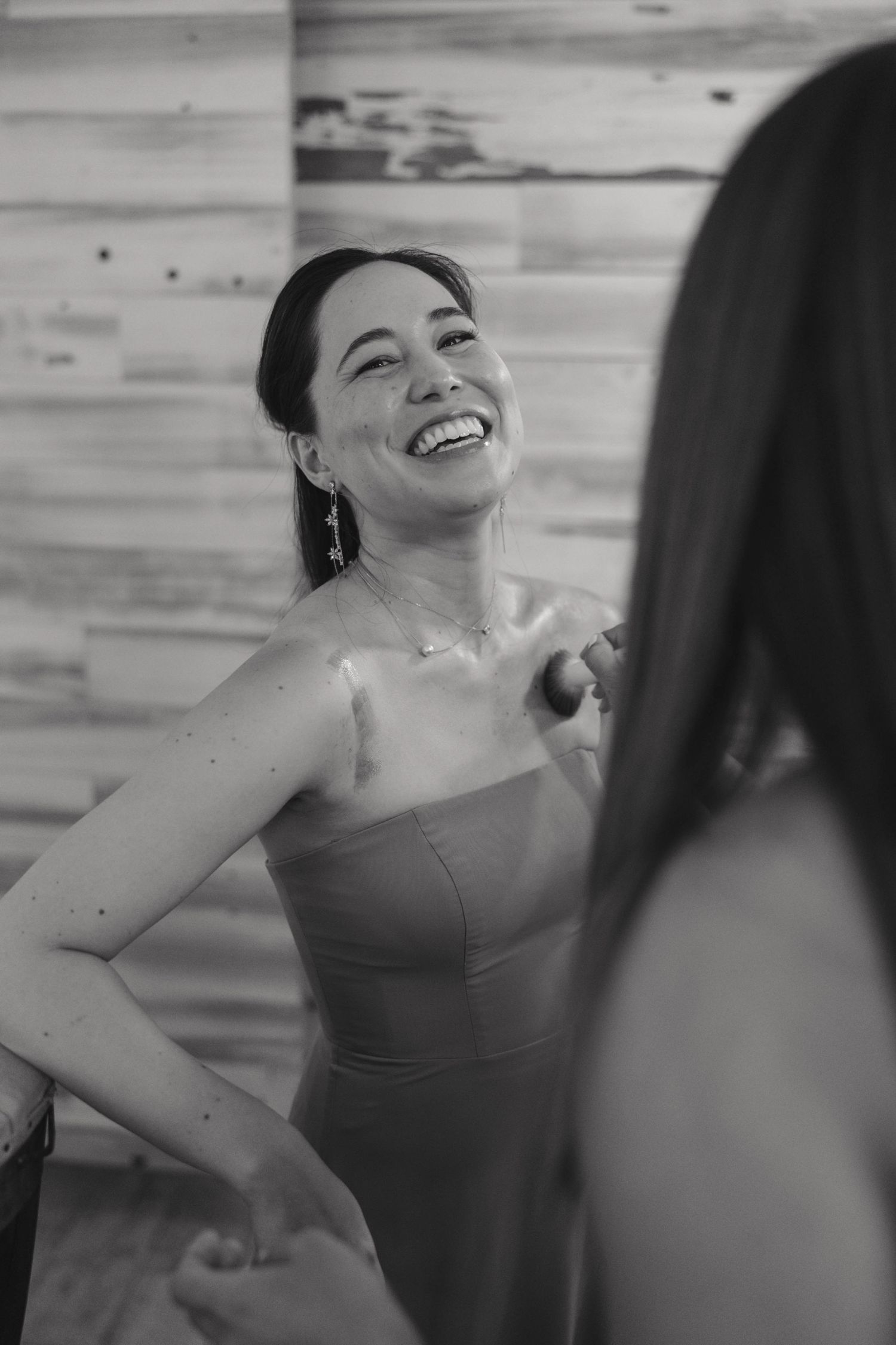 Black and white photo of bridesmaid laughing joyfully during wedding preparations.