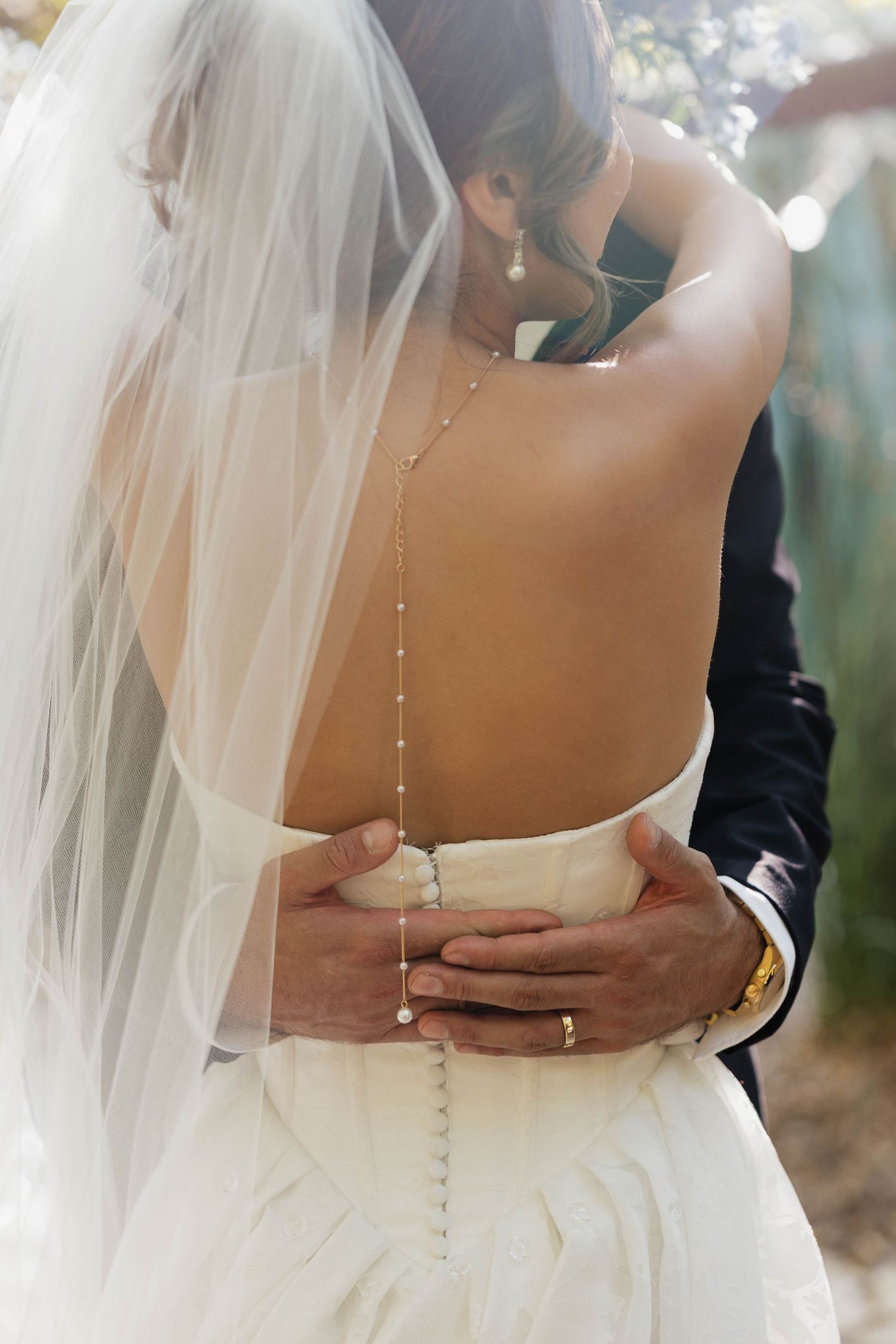 Close-up details of a bride's elegant white wedding dress with pearl buttons down the back.
