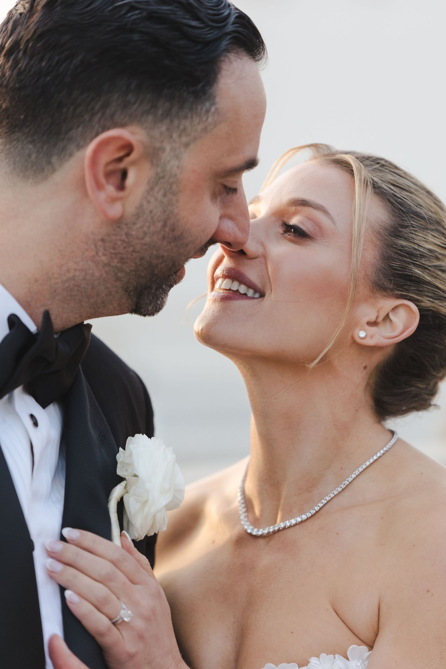 A tender moment between a couple in wedding attire sharing an intimate close-up moment outdoors.