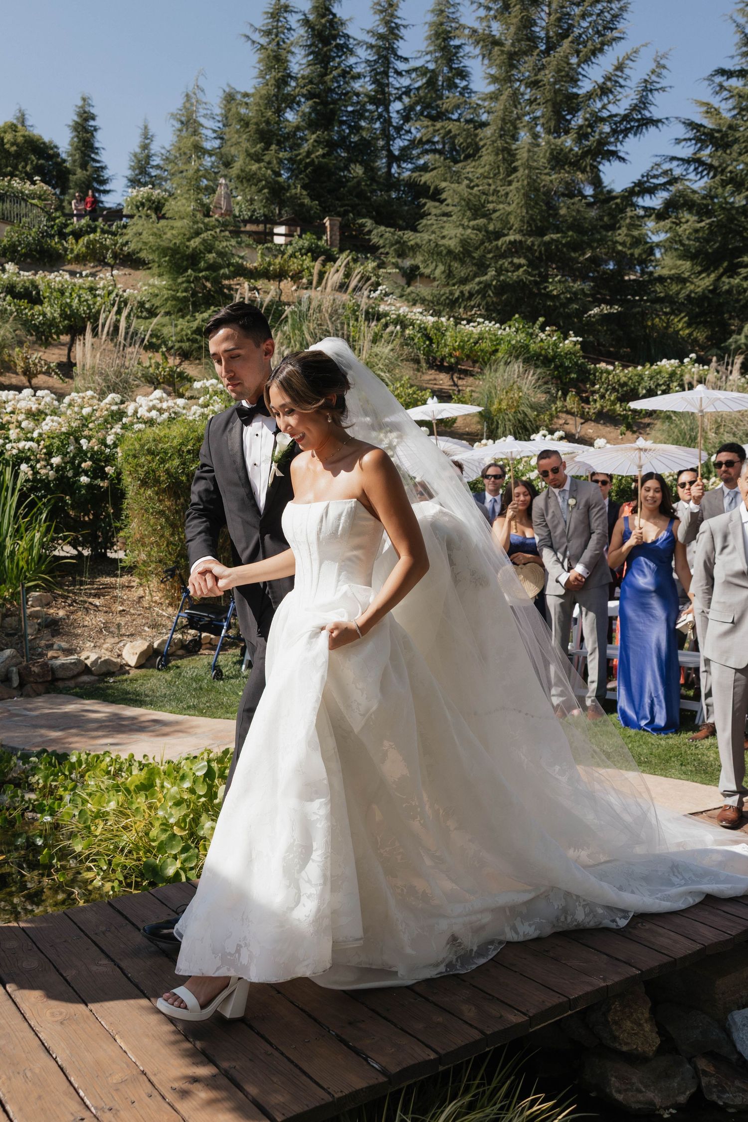 A sequence of shots showing newlyweds dancing across a wooden deck in an outdoor wedding setting with pine trees.