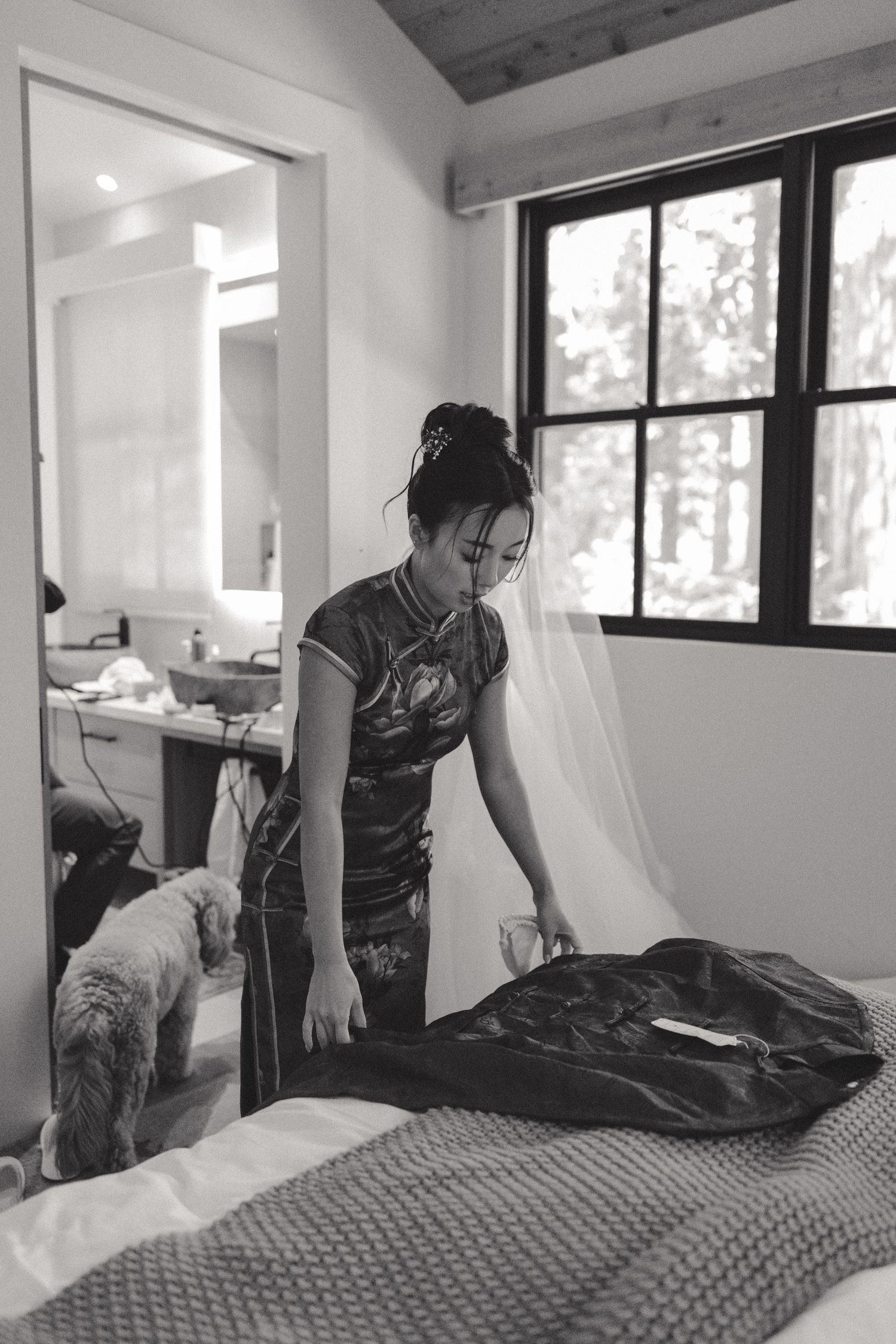 Making a bed with gray bedding and pillows in a bright modern bedroom.