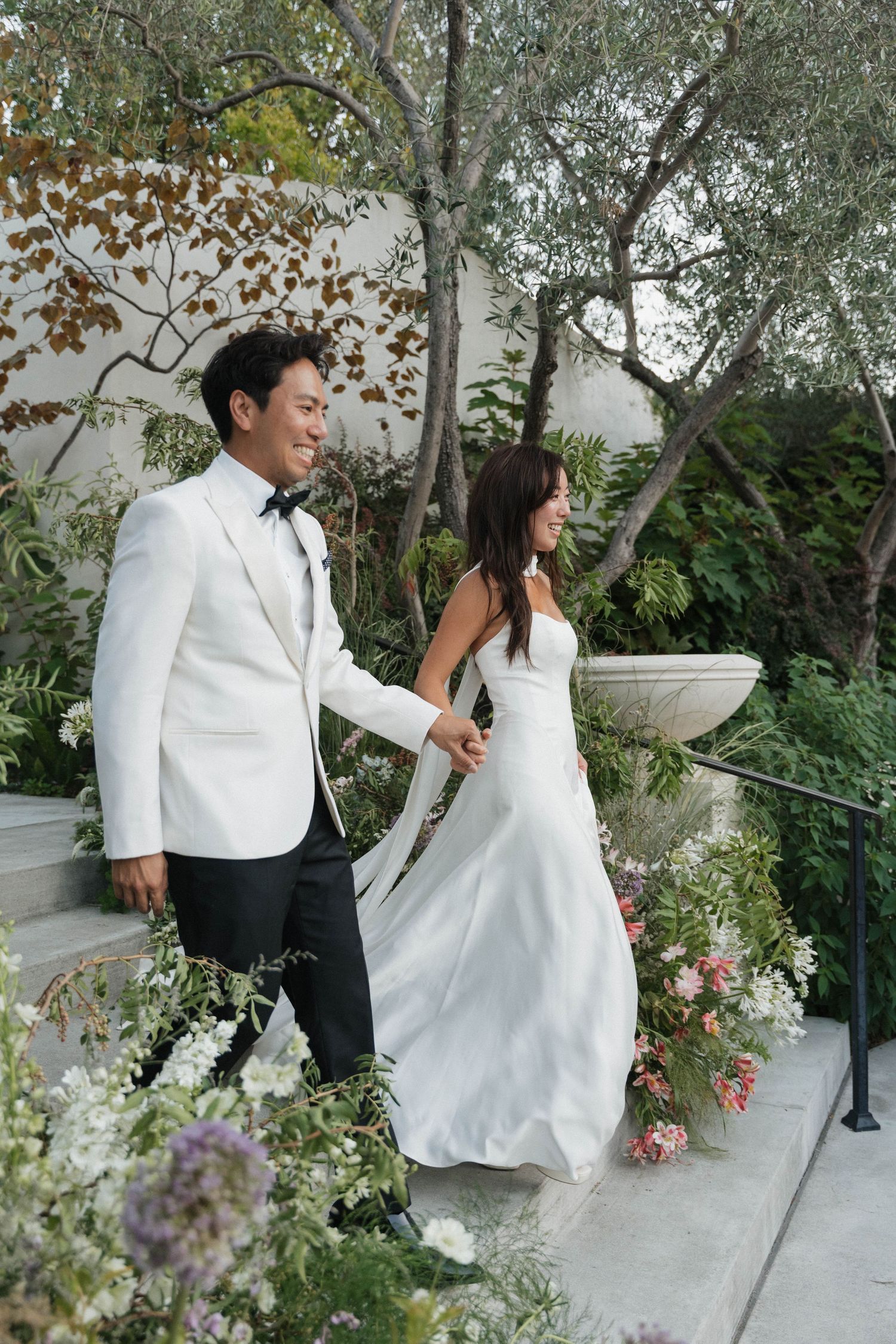 Couple sharing romantic moment on outdoor steps surrounded by flowers.