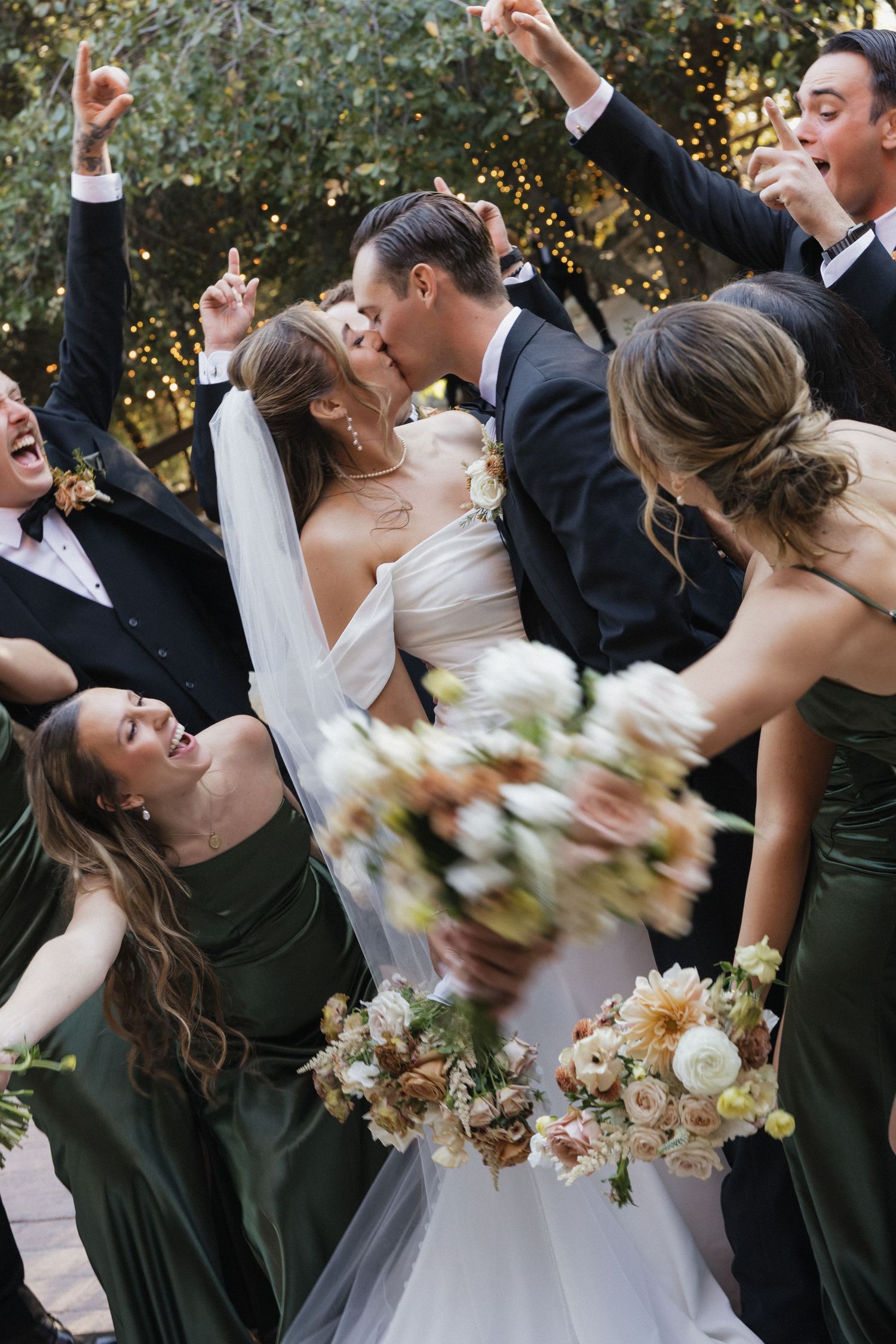 Wedding party dancing and celebrating with bouquets in formal black and white attire.