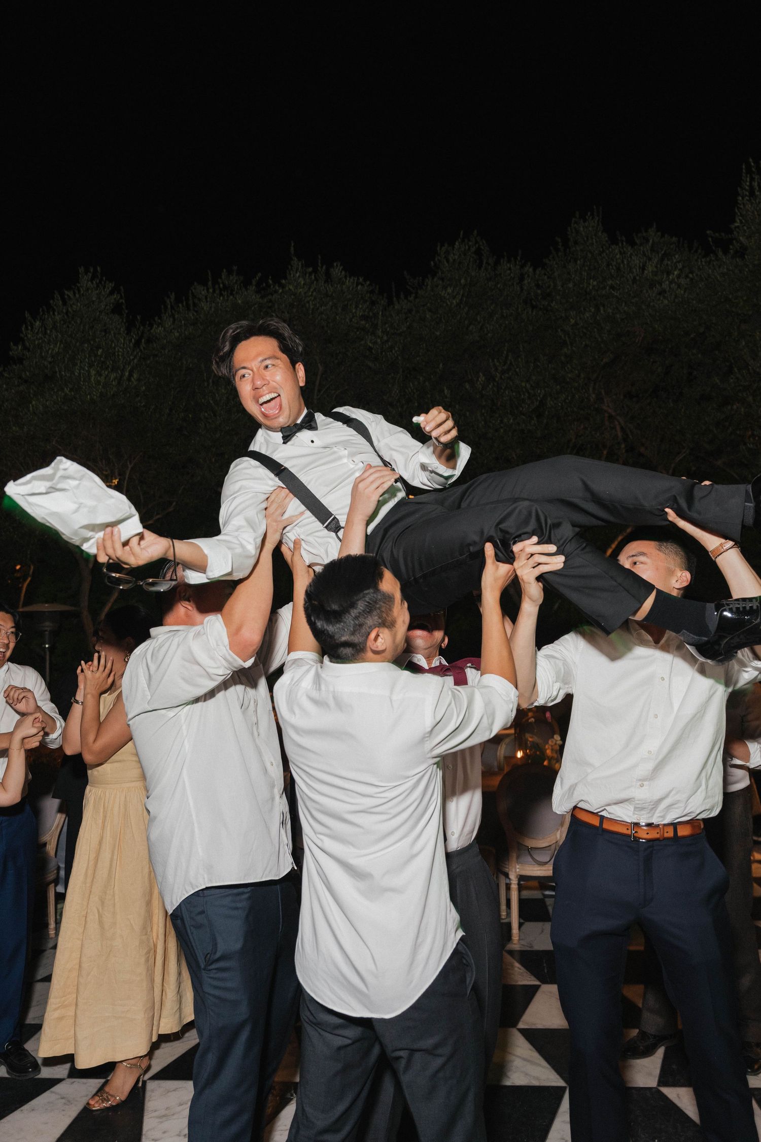 Wedding guests dancing and celebrating with energetic moves at a nighttime reception party.