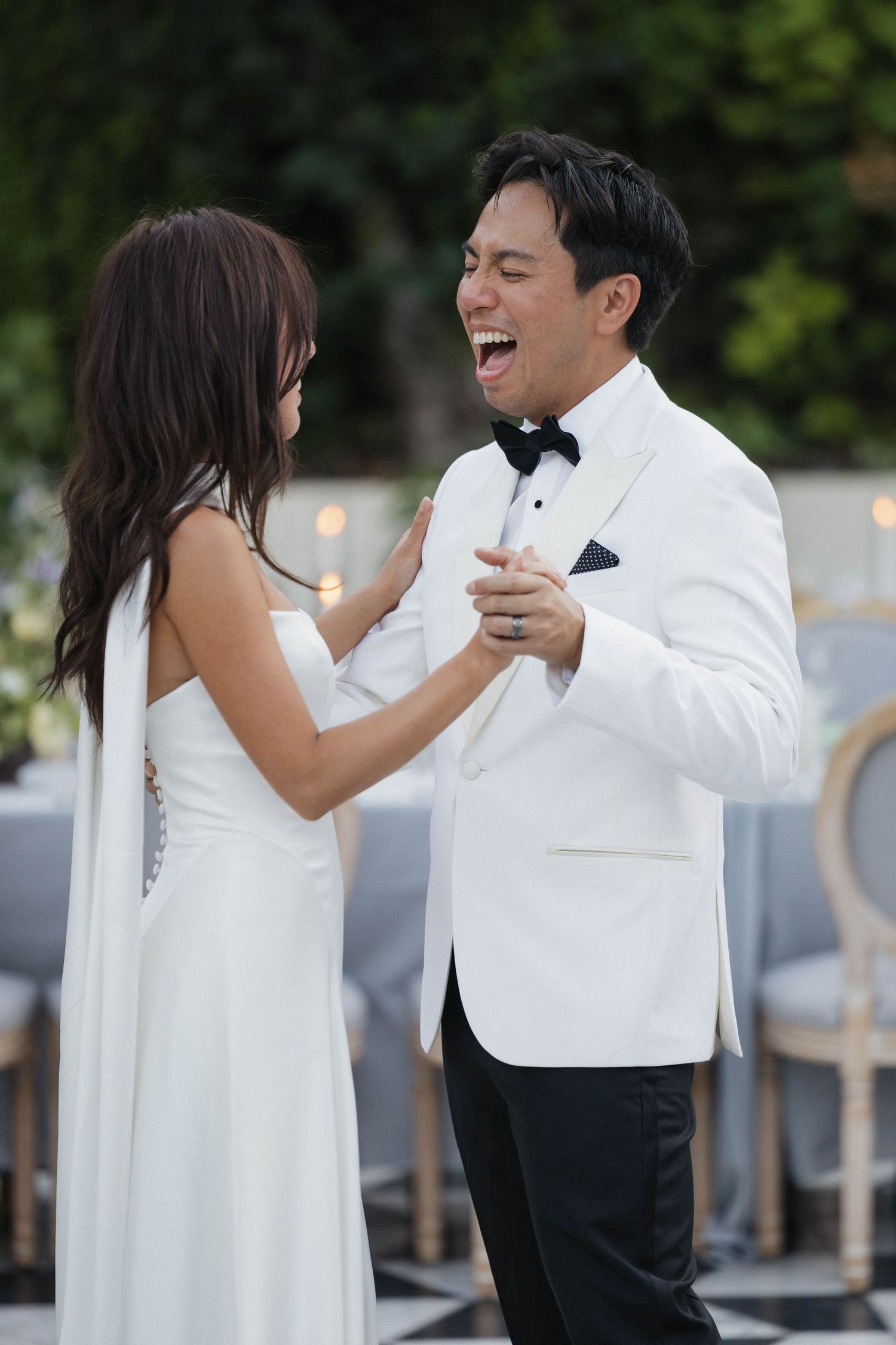 A couple shares a joyful moment during their wedding celebration outdoors.