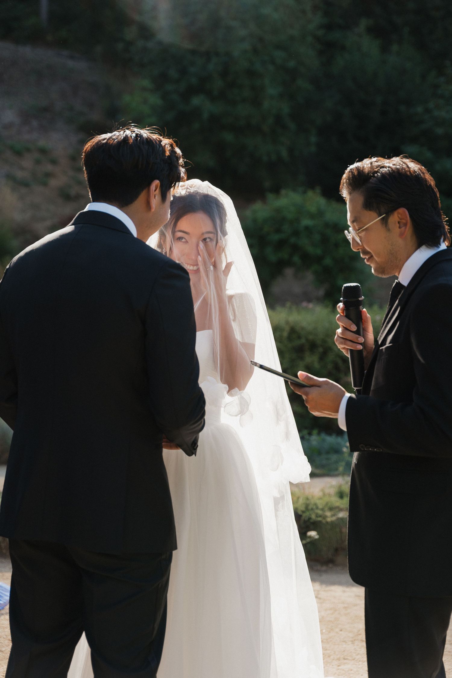 Wedding party in formal attire gathered outdoors for photography session.