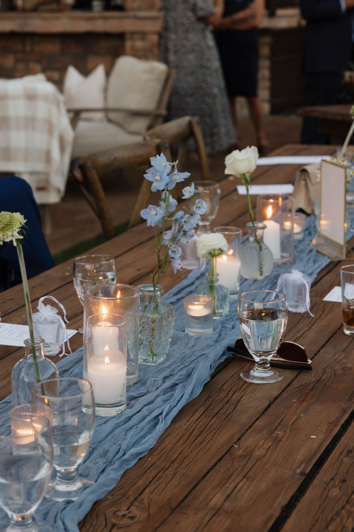 Elegant wedding table setting with blue runner, candles and delicate floral arrangements.