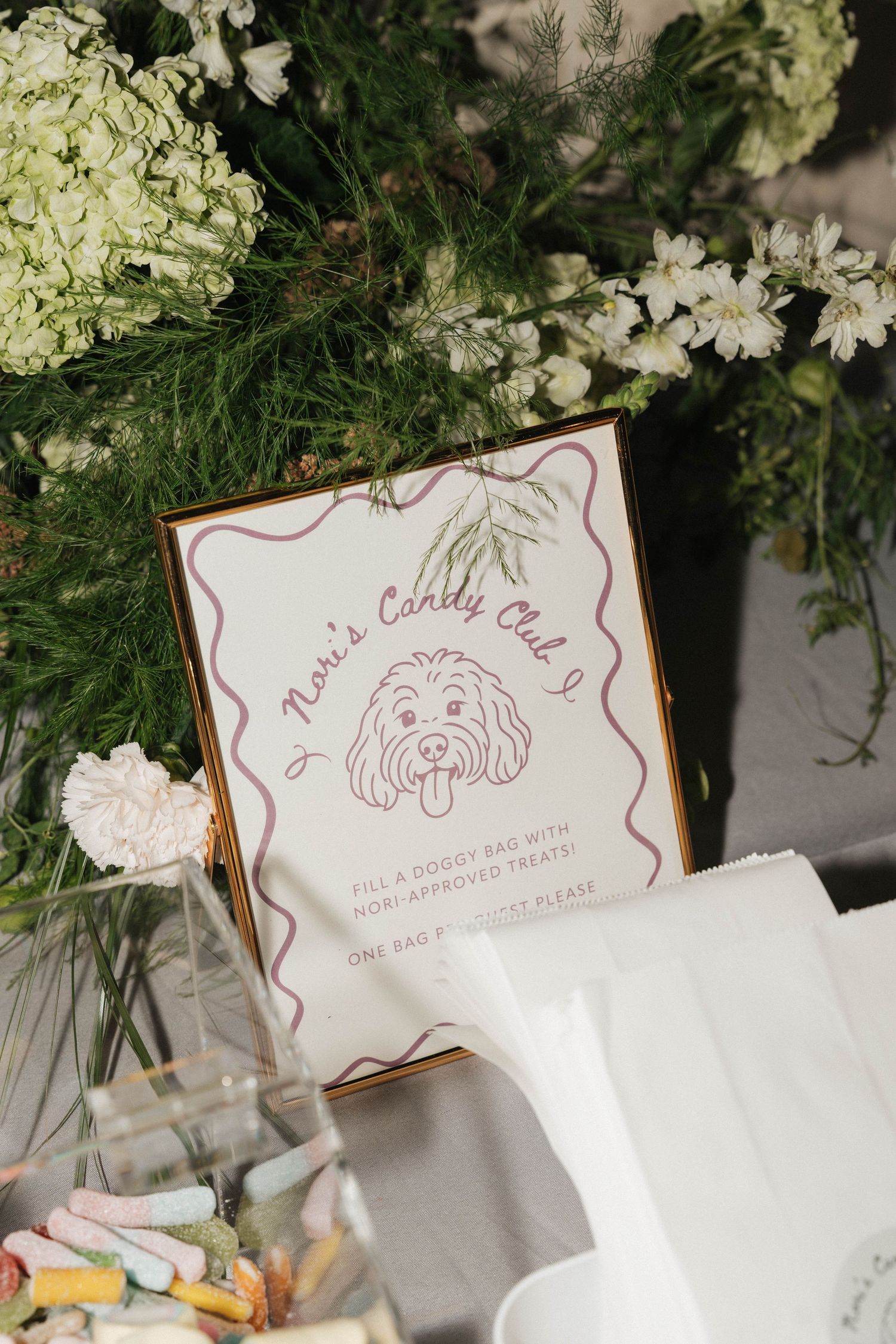 Wedding reception detail of illustrated dog portrait sign among white hydrangea flowers.