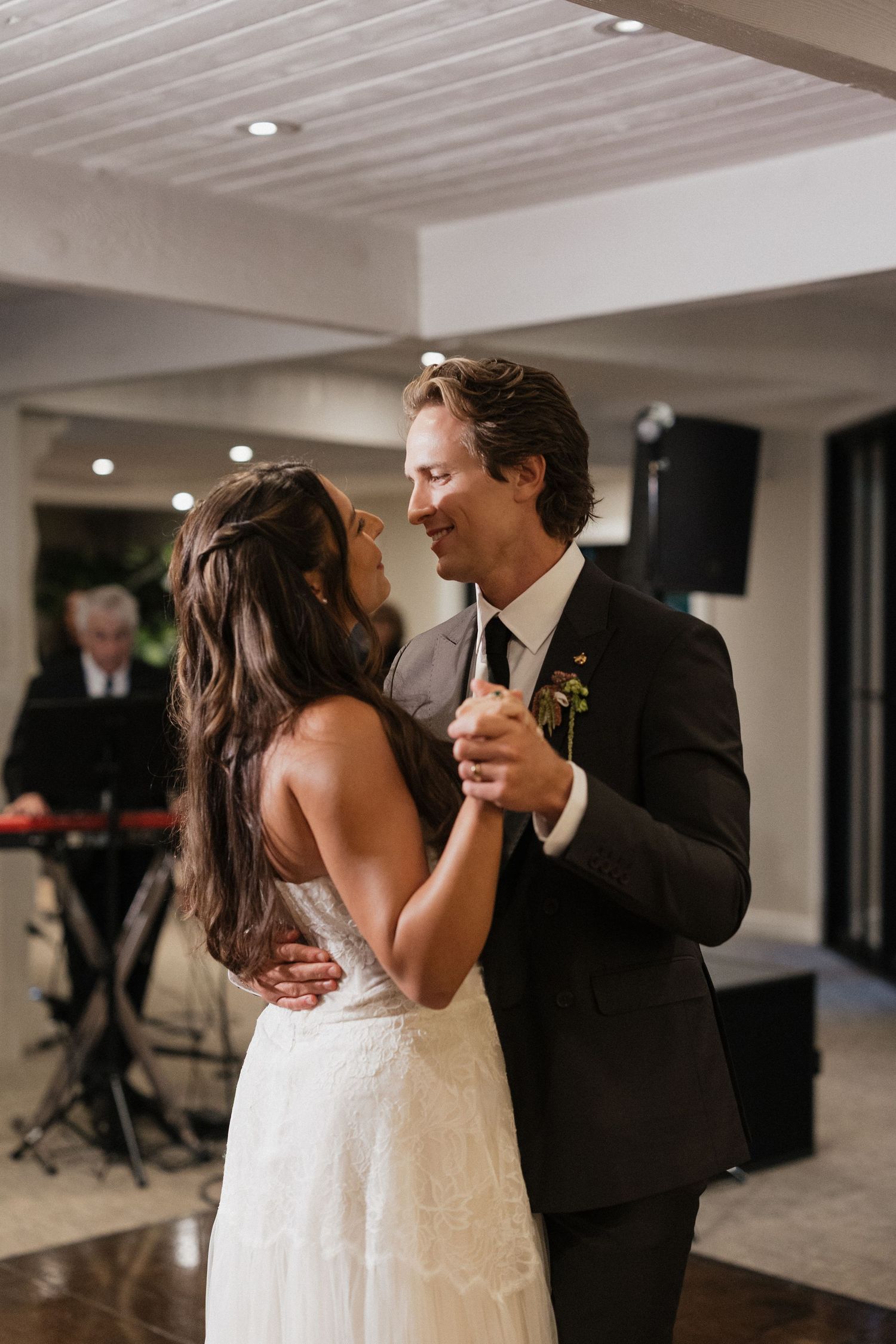 Bride and groom share an intimate first dance smiling at each other at their wedding reception.