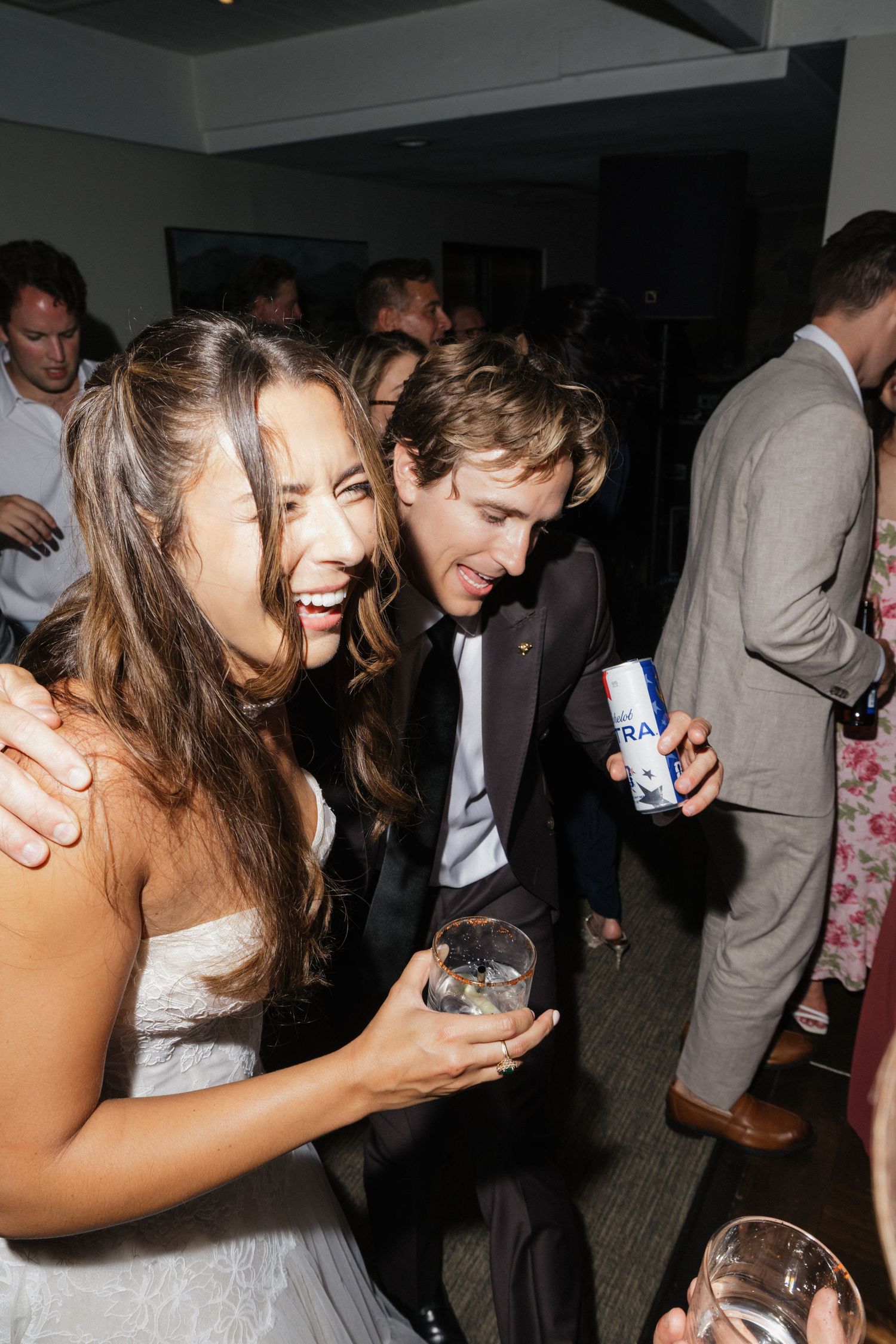 Bride and groom laughing together at lively wedding reception party.