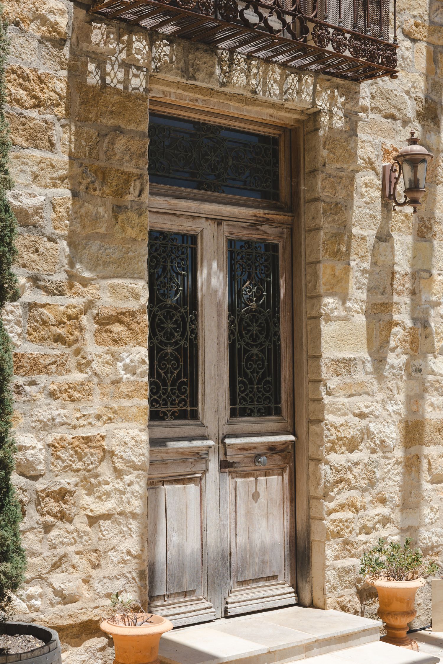 A row of traditional style wooden doors with ornate iron grilles set in a limestone or sandstone building facade.