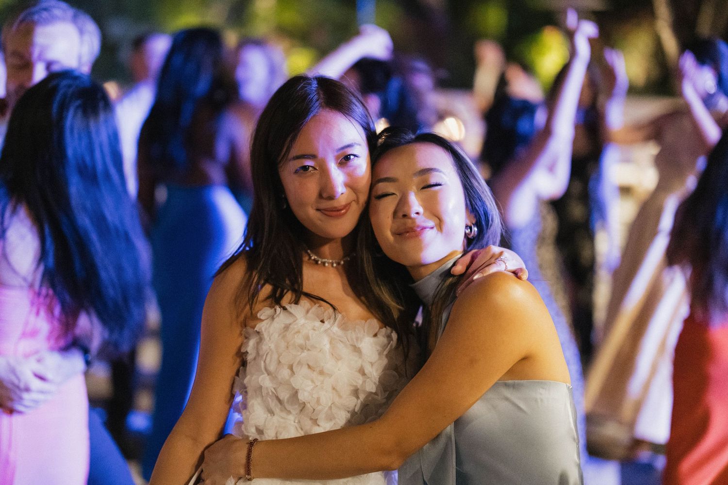 Joyful celebration moment at evening wedding reception with blue lighting.