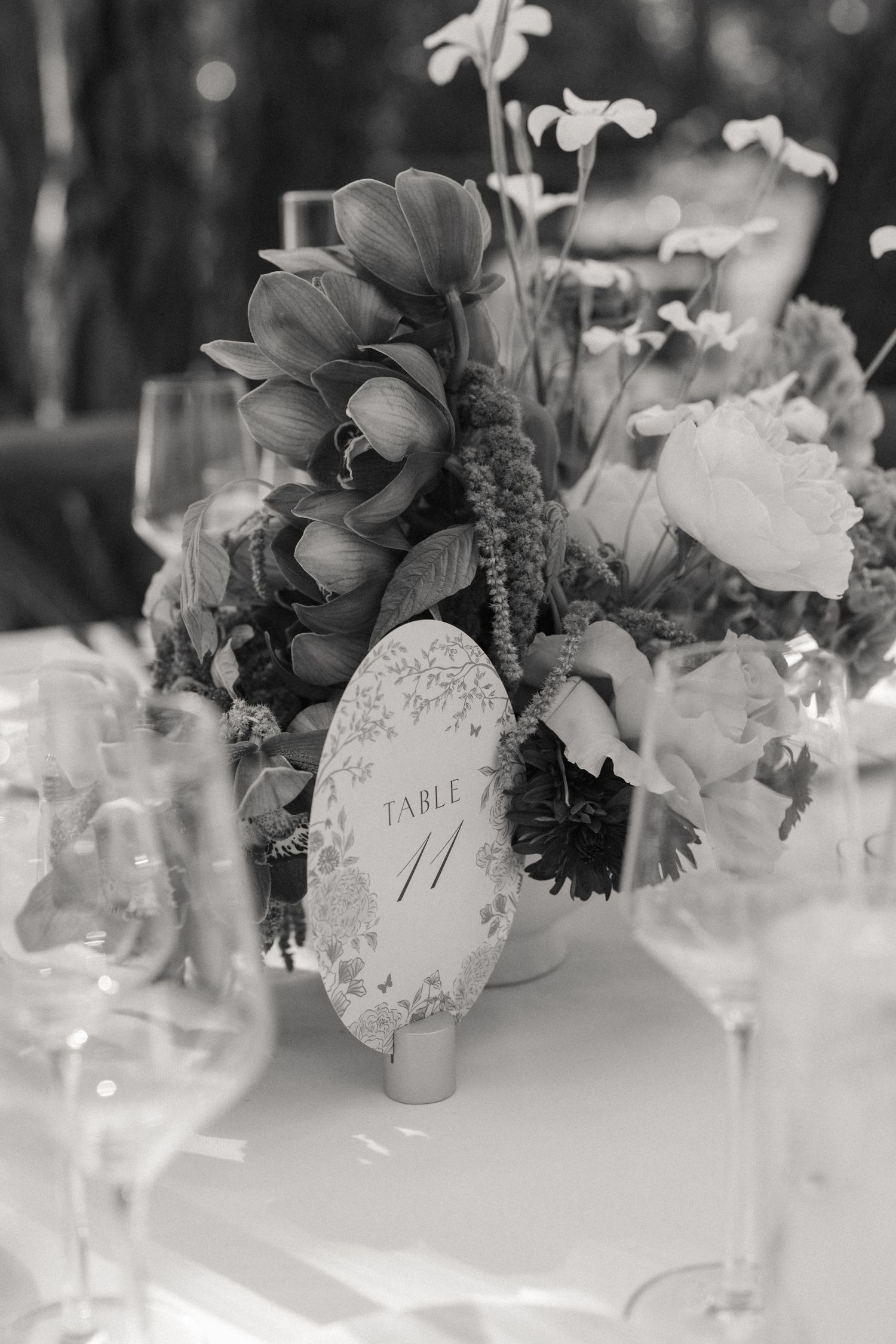 Black and white wedding table centerpiece with lush florals and elegant table number card.