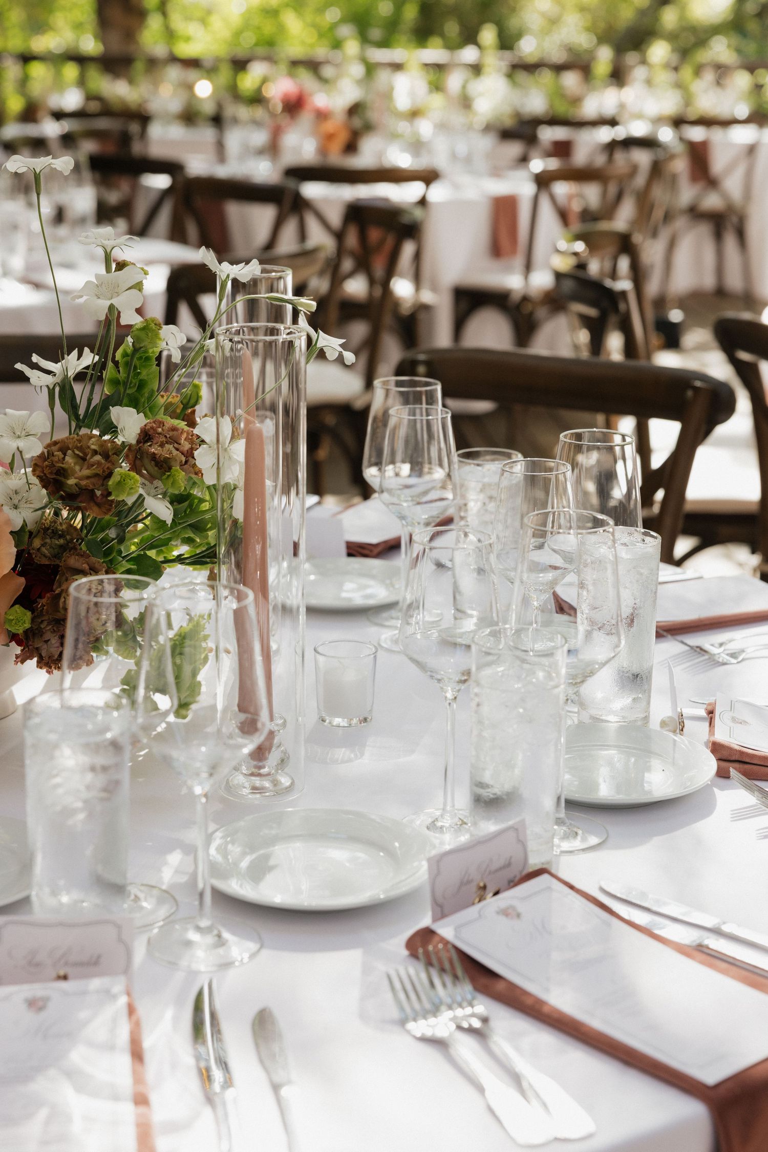 Elegant outdoor wedding reception table with white linens and floral centerpieces.