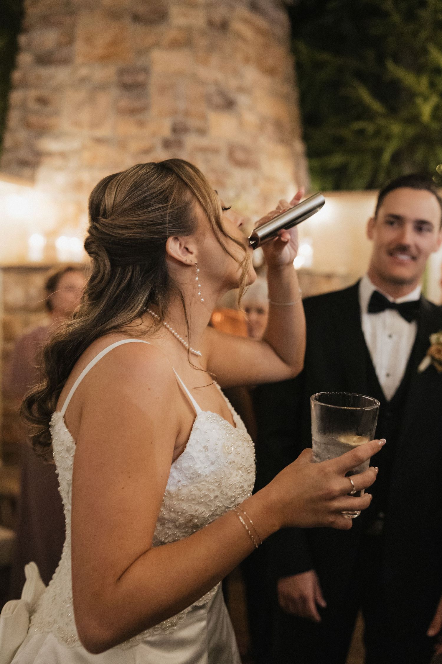 A celebratory moment at a wedding reception with drinks and laughter near a stone wall.