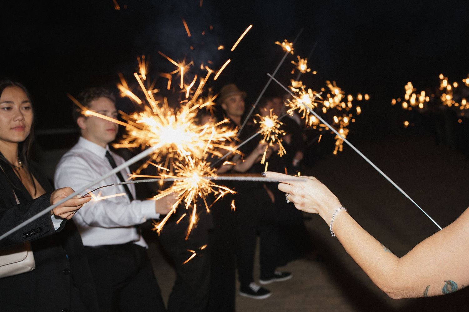 Sparklers creating magical light trails at nighttime wedding celebration.
