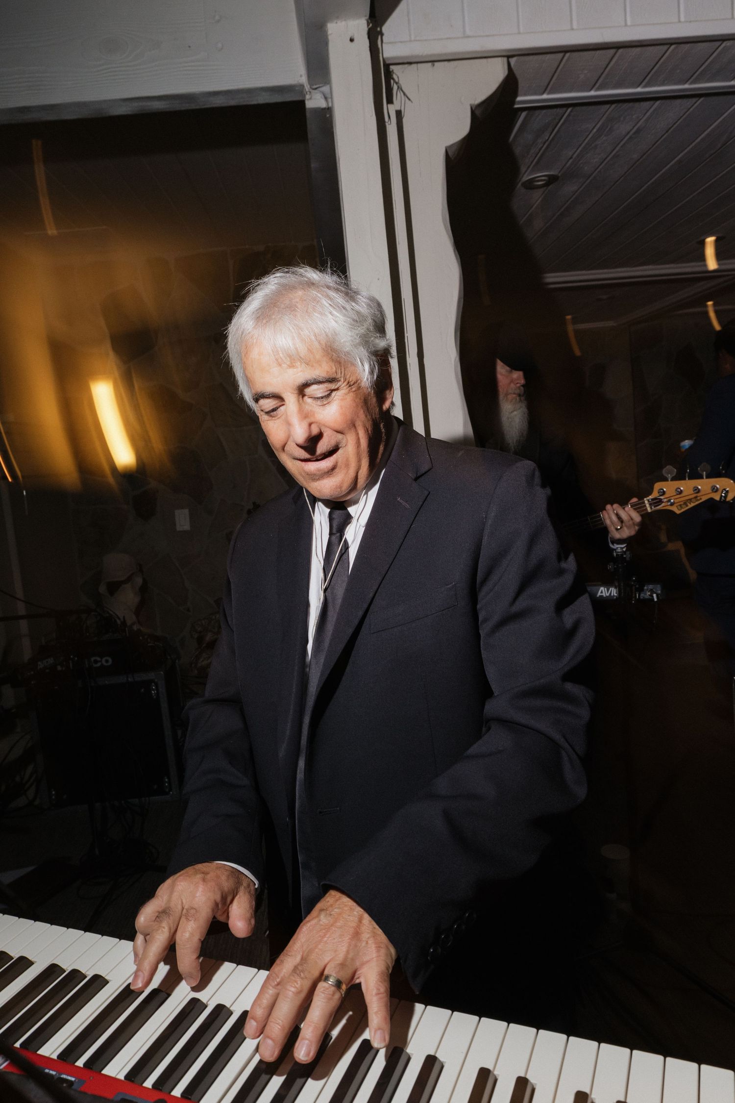 Elderly musician passionately plays grand piano at elegant wedding reception entertainment.