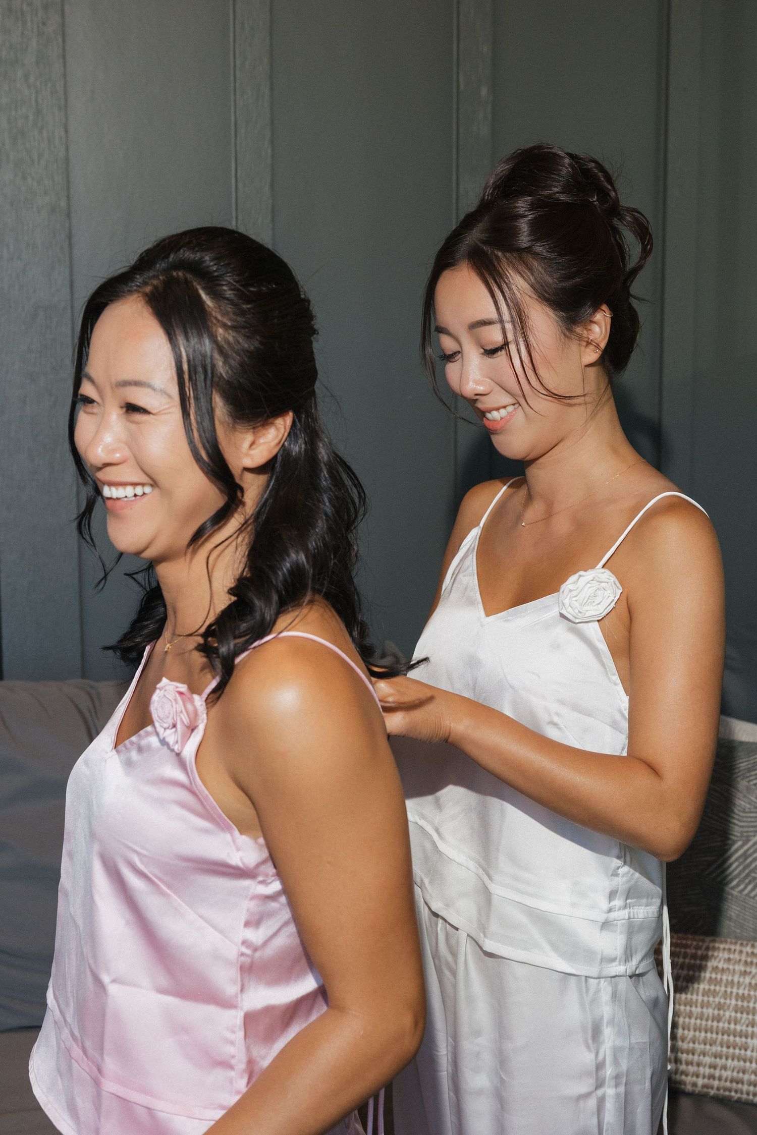 Two friends in pink and white tops share a joyful moment of laughter together in a candid photo sequence.