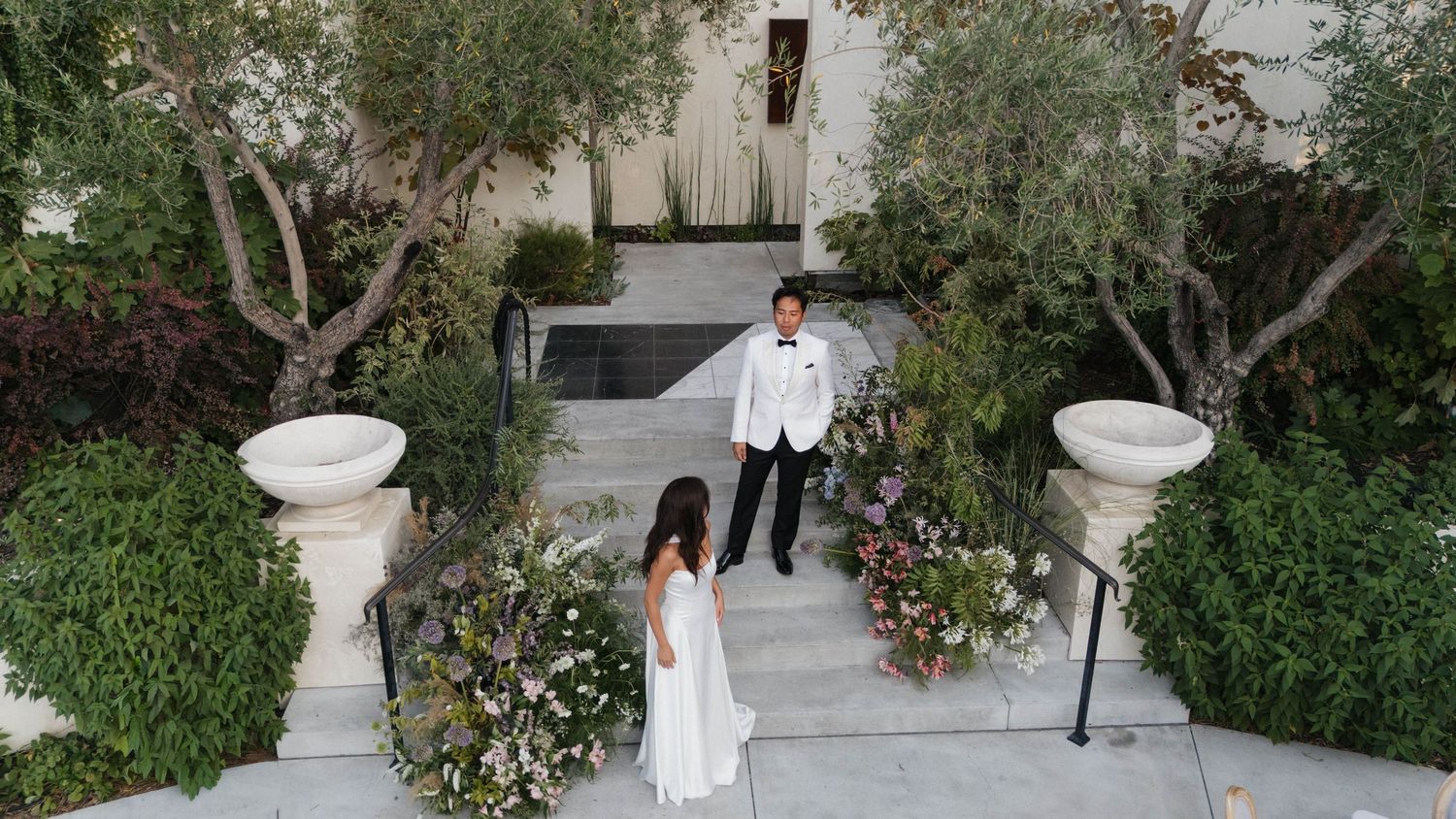 An elegant outdoor wedding venue with white pillars and lush greenery.