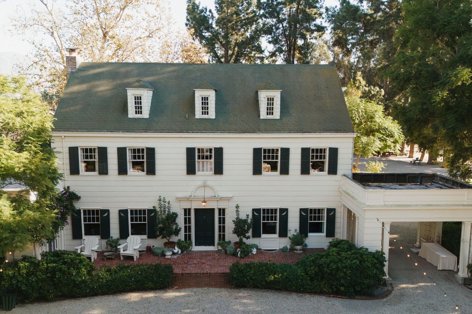 Colonial-style white house with black shutters and dormers photographed in a panoramic view.