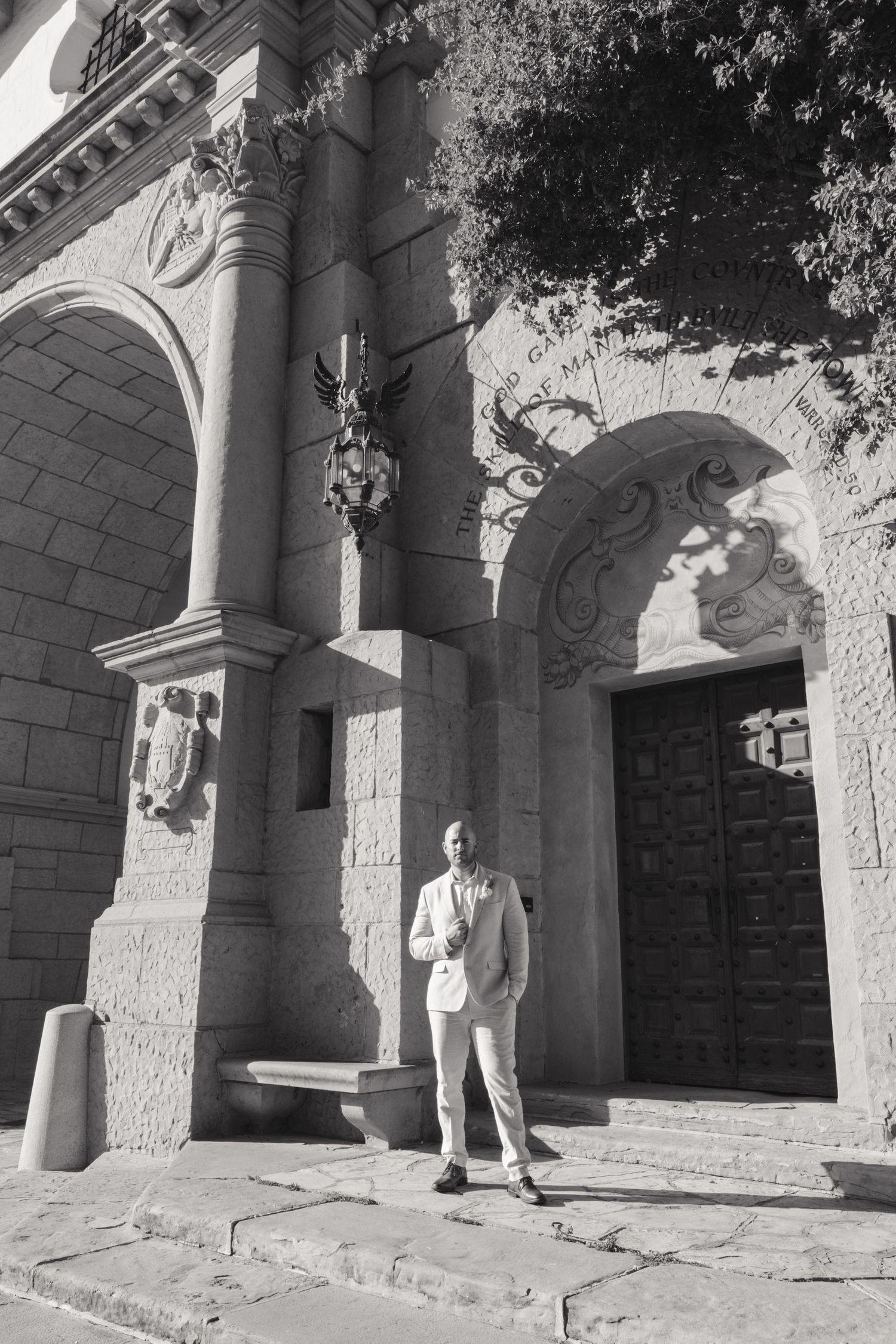Black and white photograph of a stone archway entrance with pillars and architectural details.