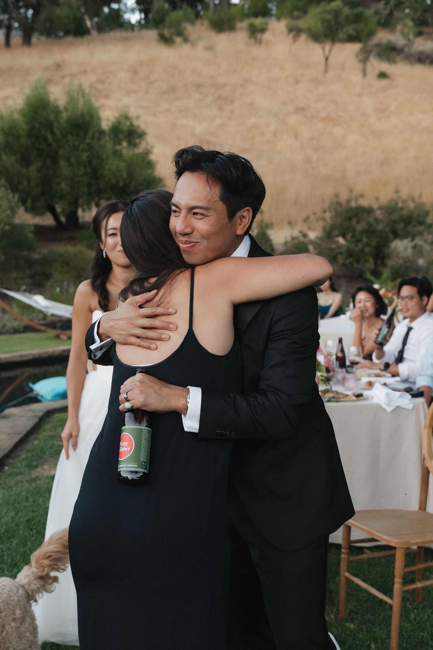 Wedding reception candid moment of guests embracing outdoors.