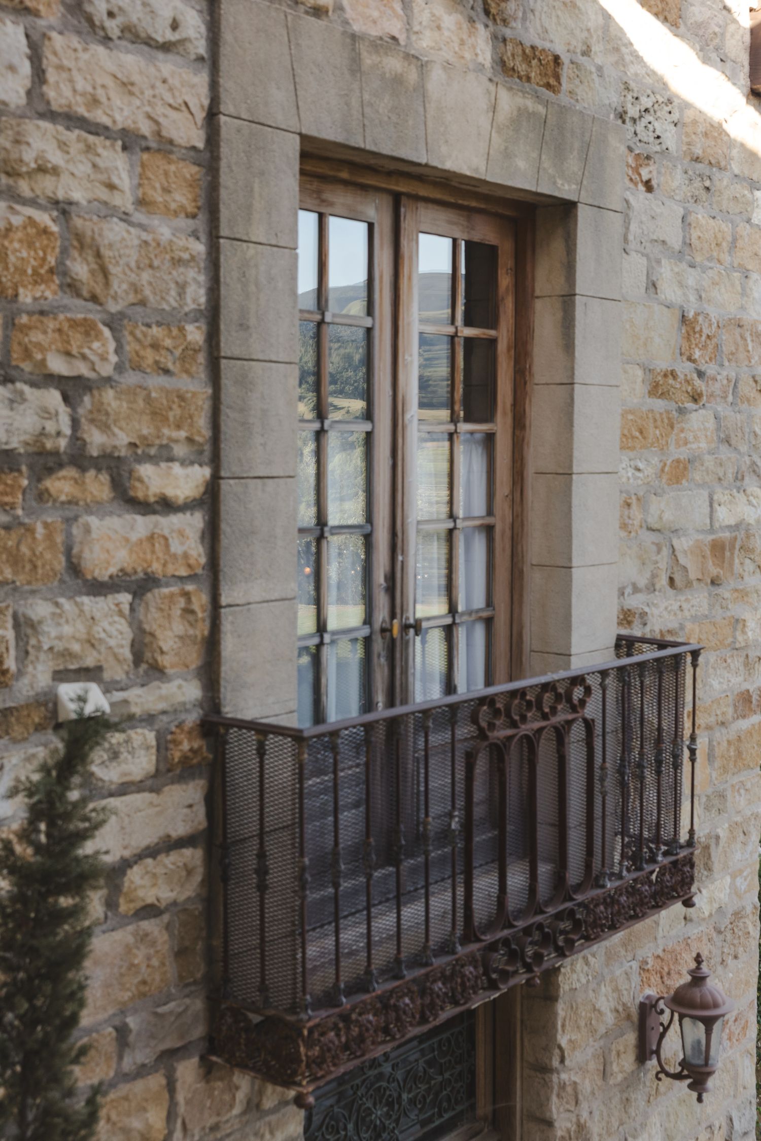 Stone building exterior featuring ornate wrought iron balcony railings and vintage windows.