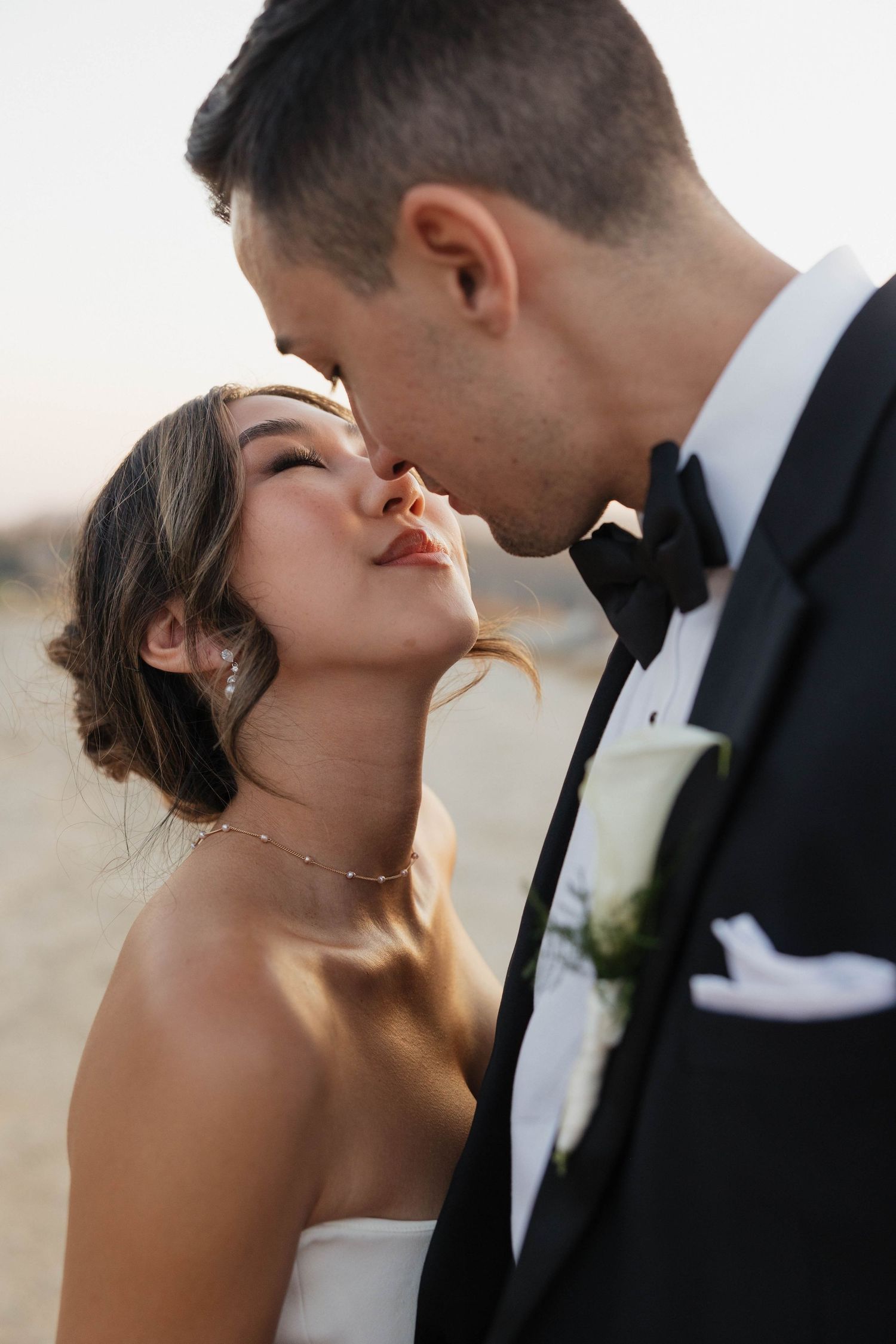 Romantic close-up portrait of couple sharing intimate moment in formal wedding attire.