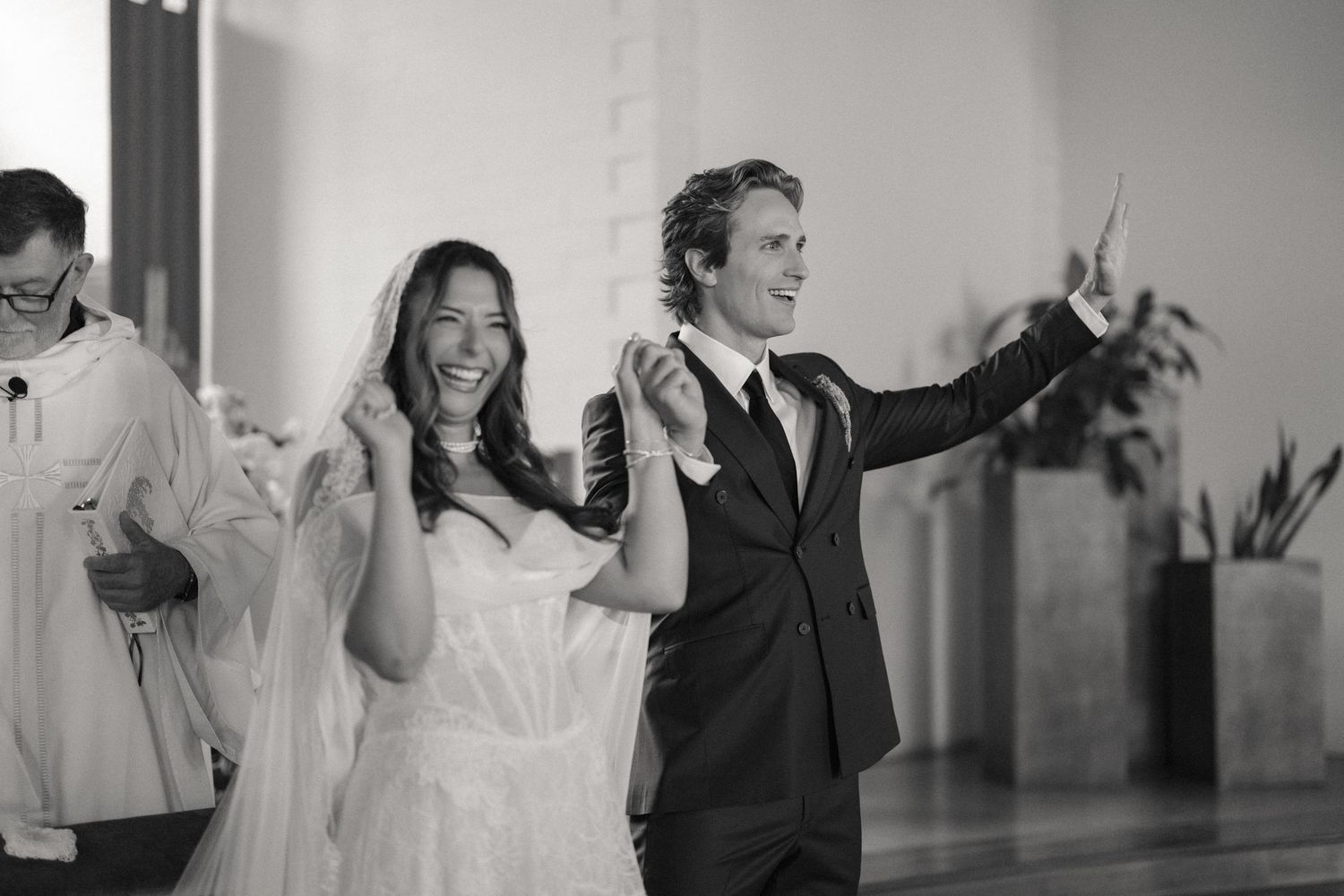 Joyful bride and groom celebrate their wedding ceremony exit in a classic black and white photo.