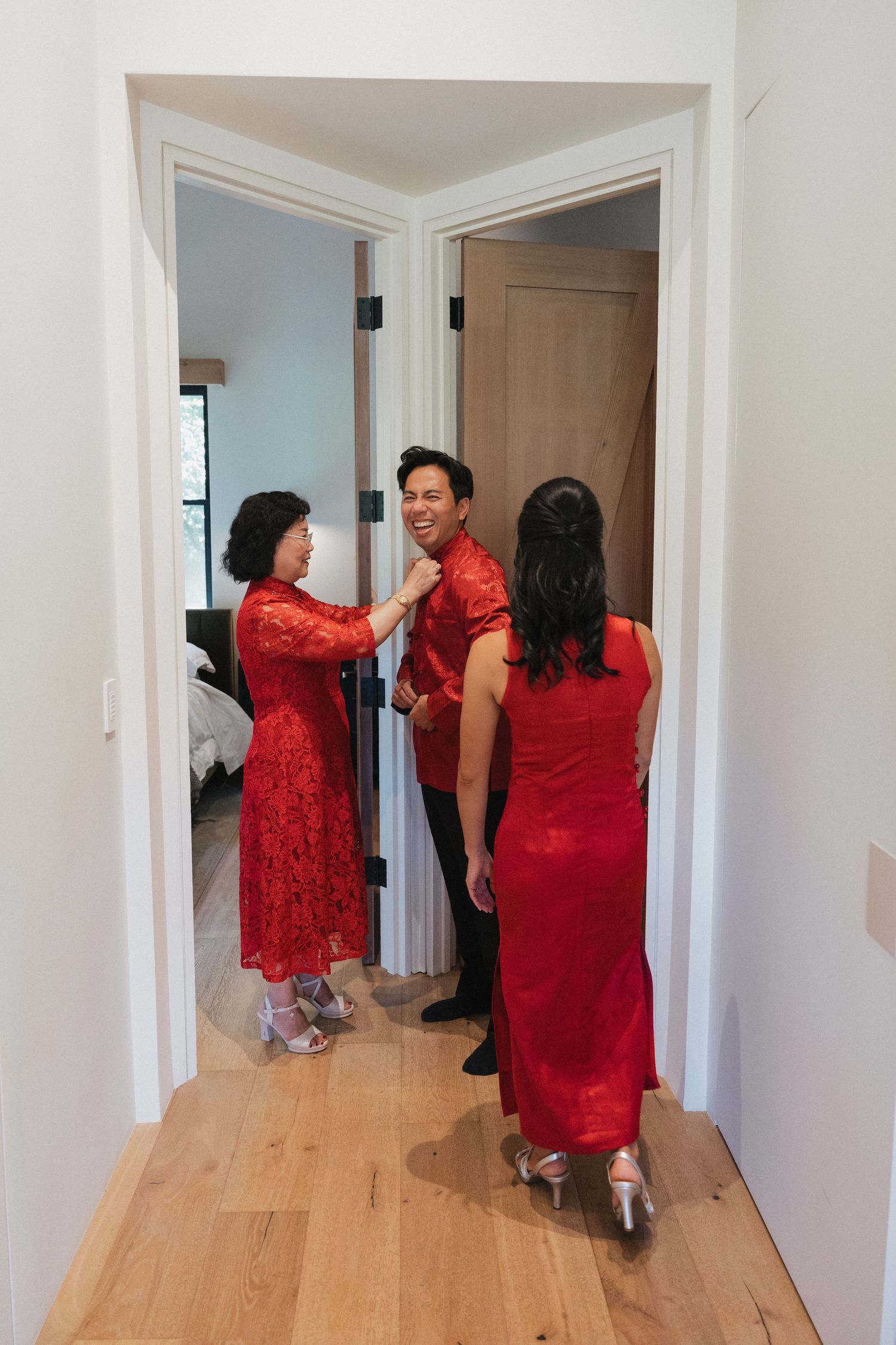 People in red traditional dresses walking down a hallway with wooden flooring.