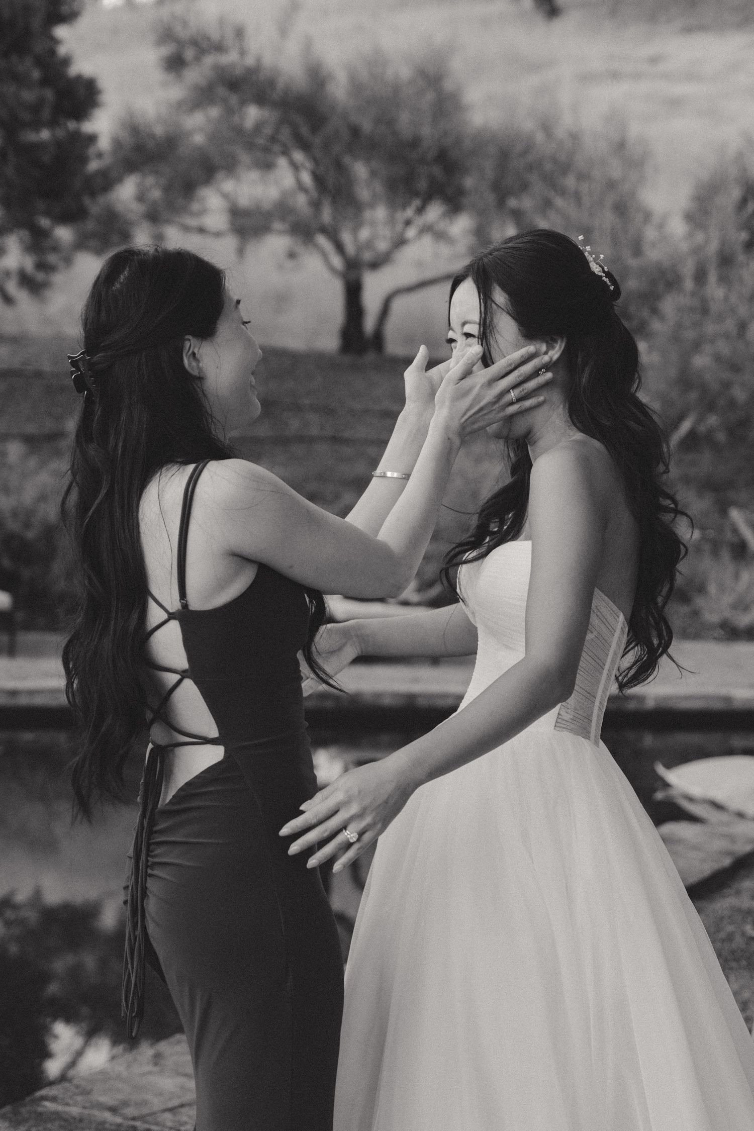 Black and white photo of emotional moment between bride and woman in black dress.