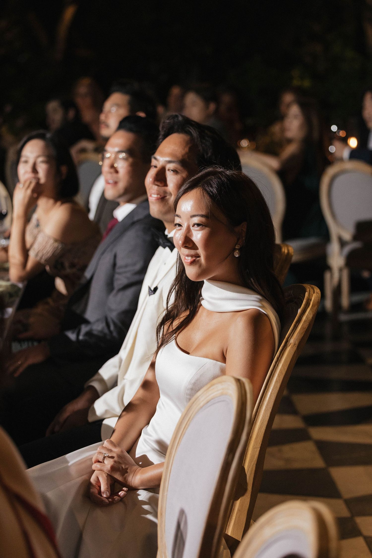 Wedding guests seated at reception during evening celebration.