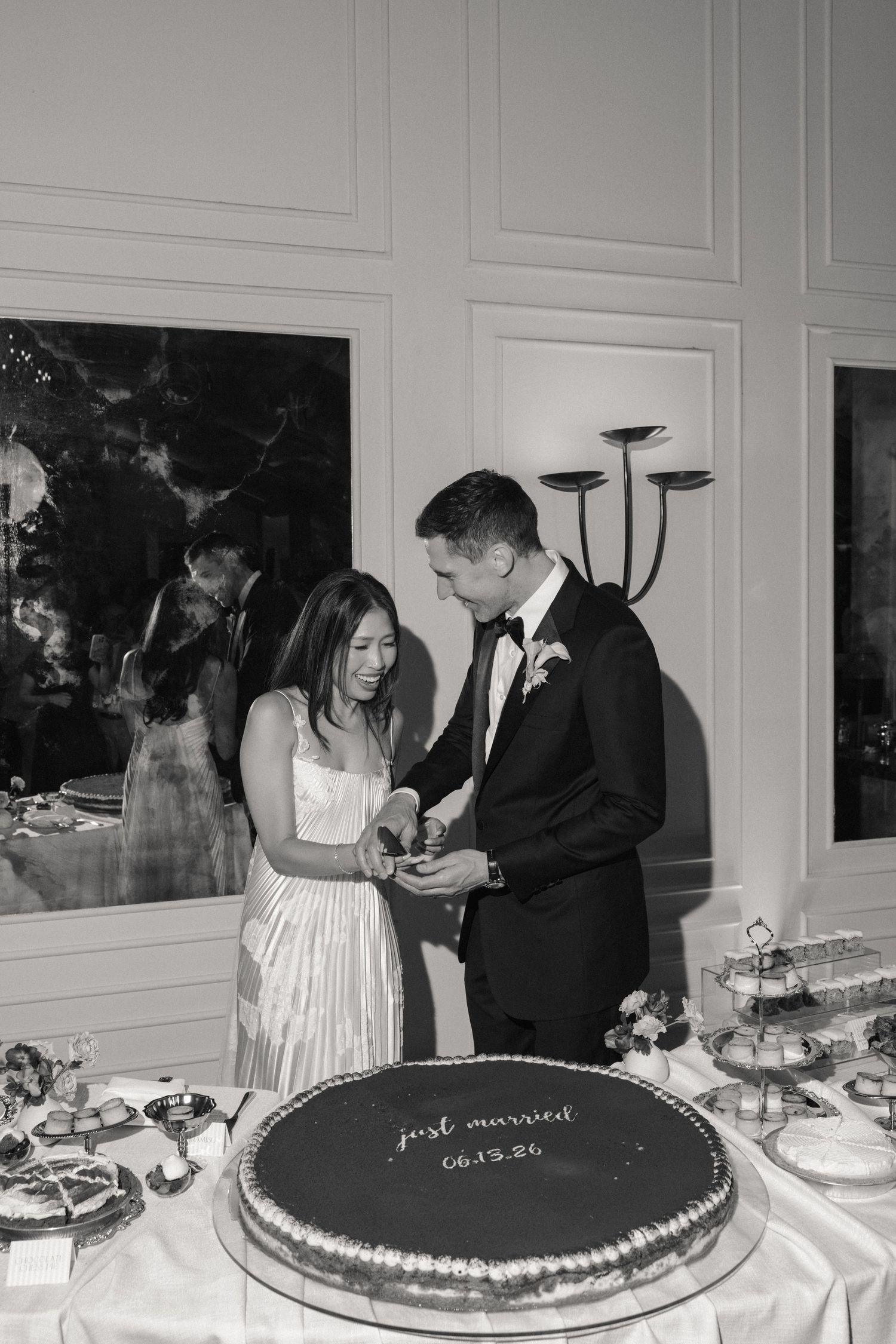 Bride and groom cut their Just Married cake dated 06.13.26 at elegant wedding reception in black and white photo.