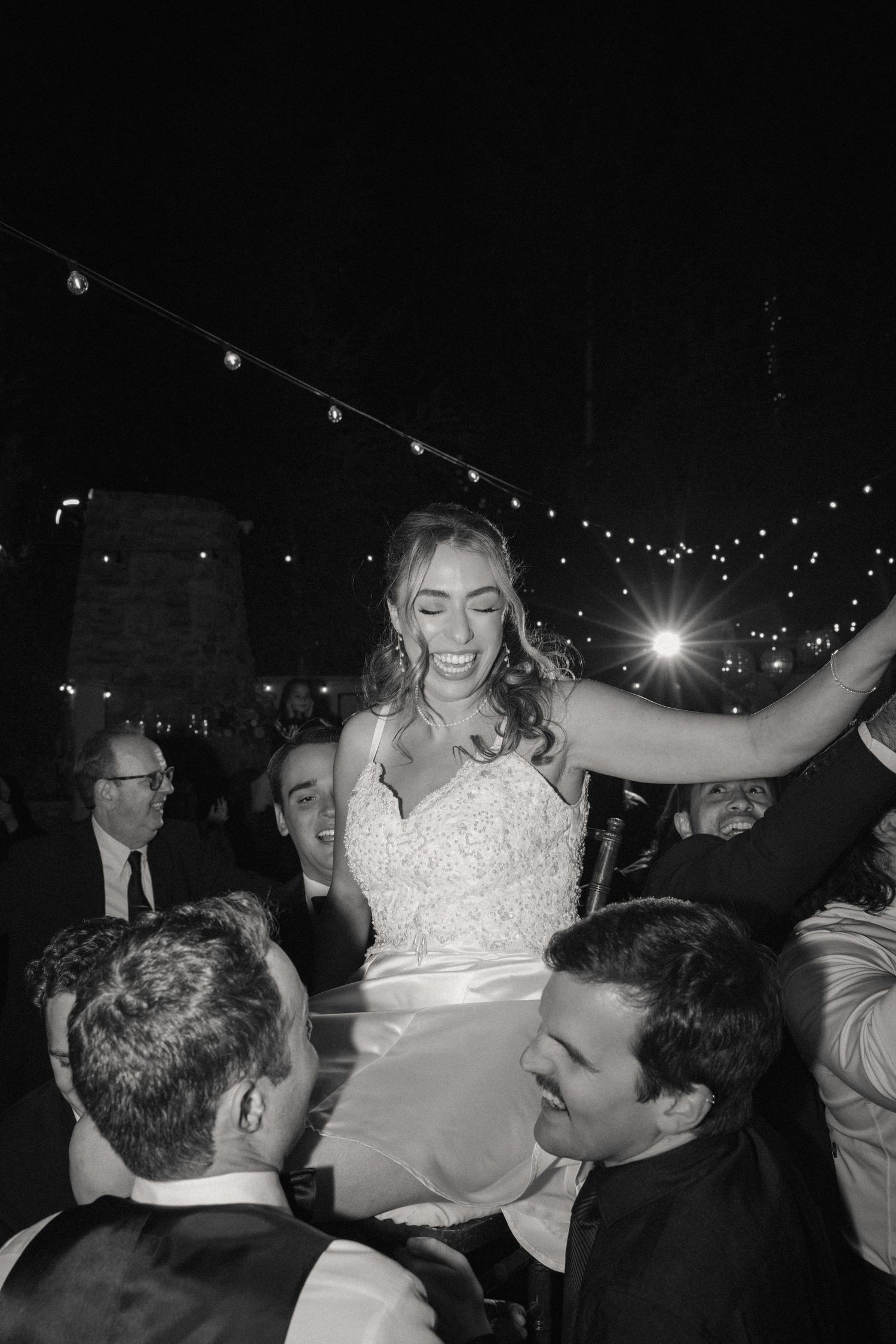 Wedding reception dance party scene with string lights and celebratory atmosphere.