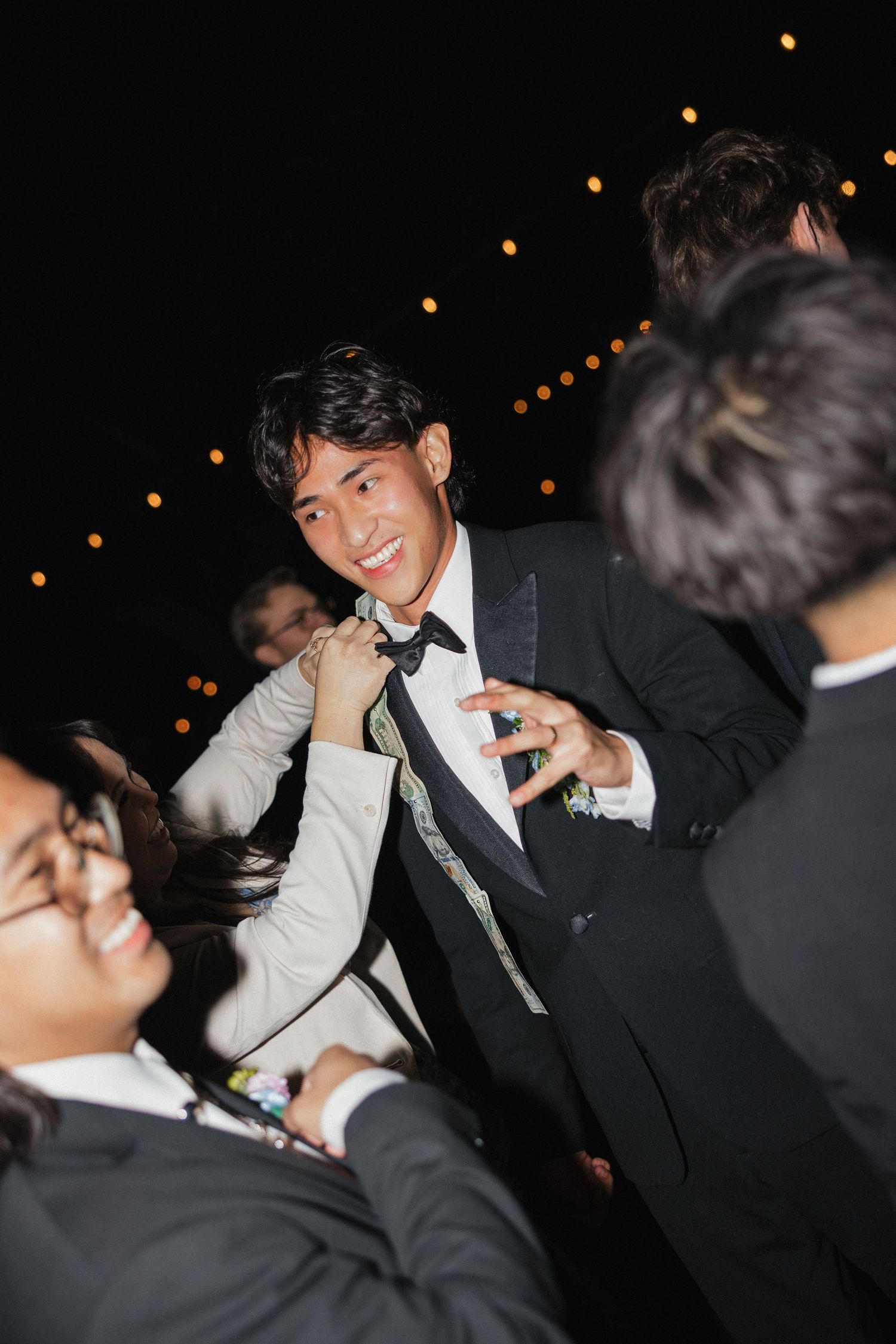 Wedding party members in formal attire laugh and celebrate at a dimly lit reception.
