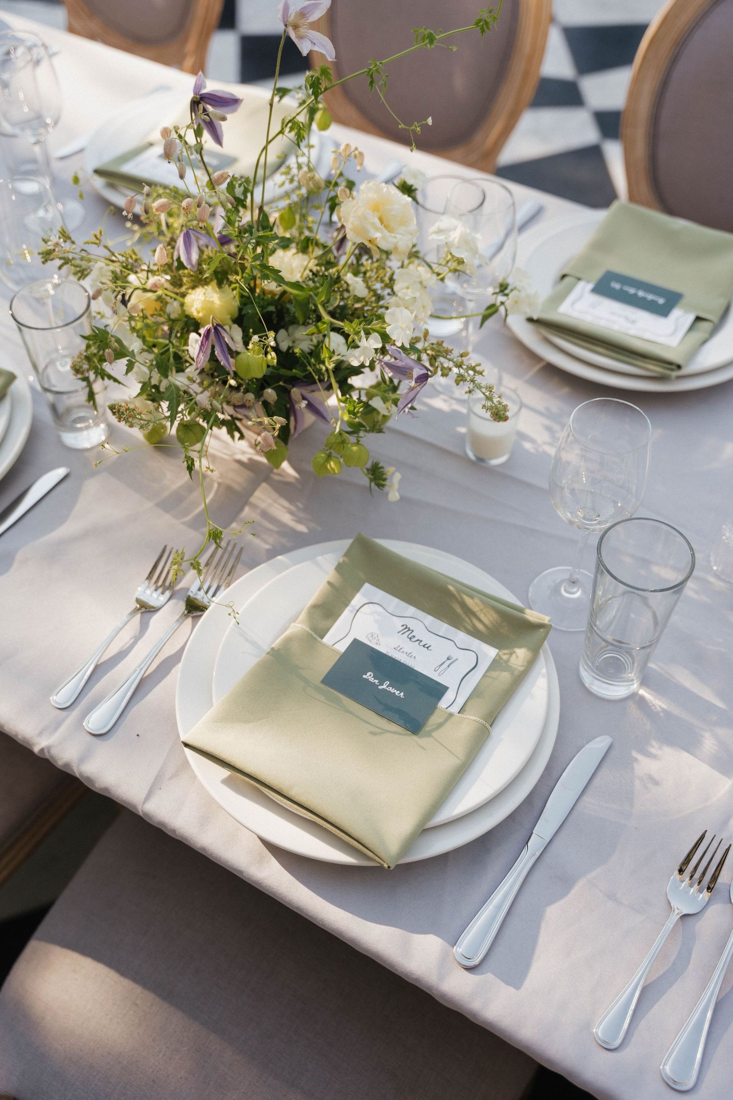 Elegant wedding table setting with white linens and delicate floral centerpieces.