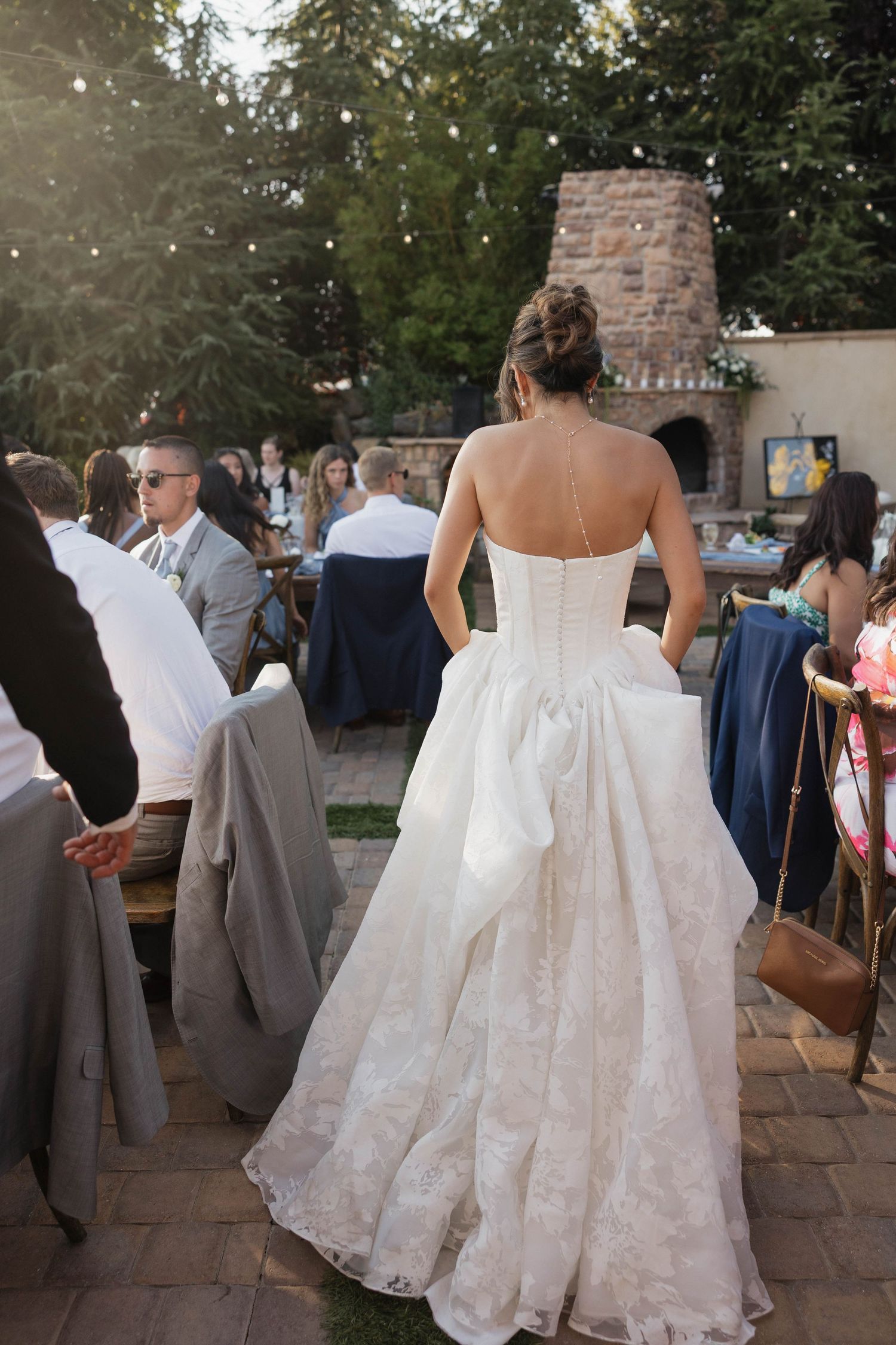 Back view of bride's detailed lace wedding gown during outdoor reception.