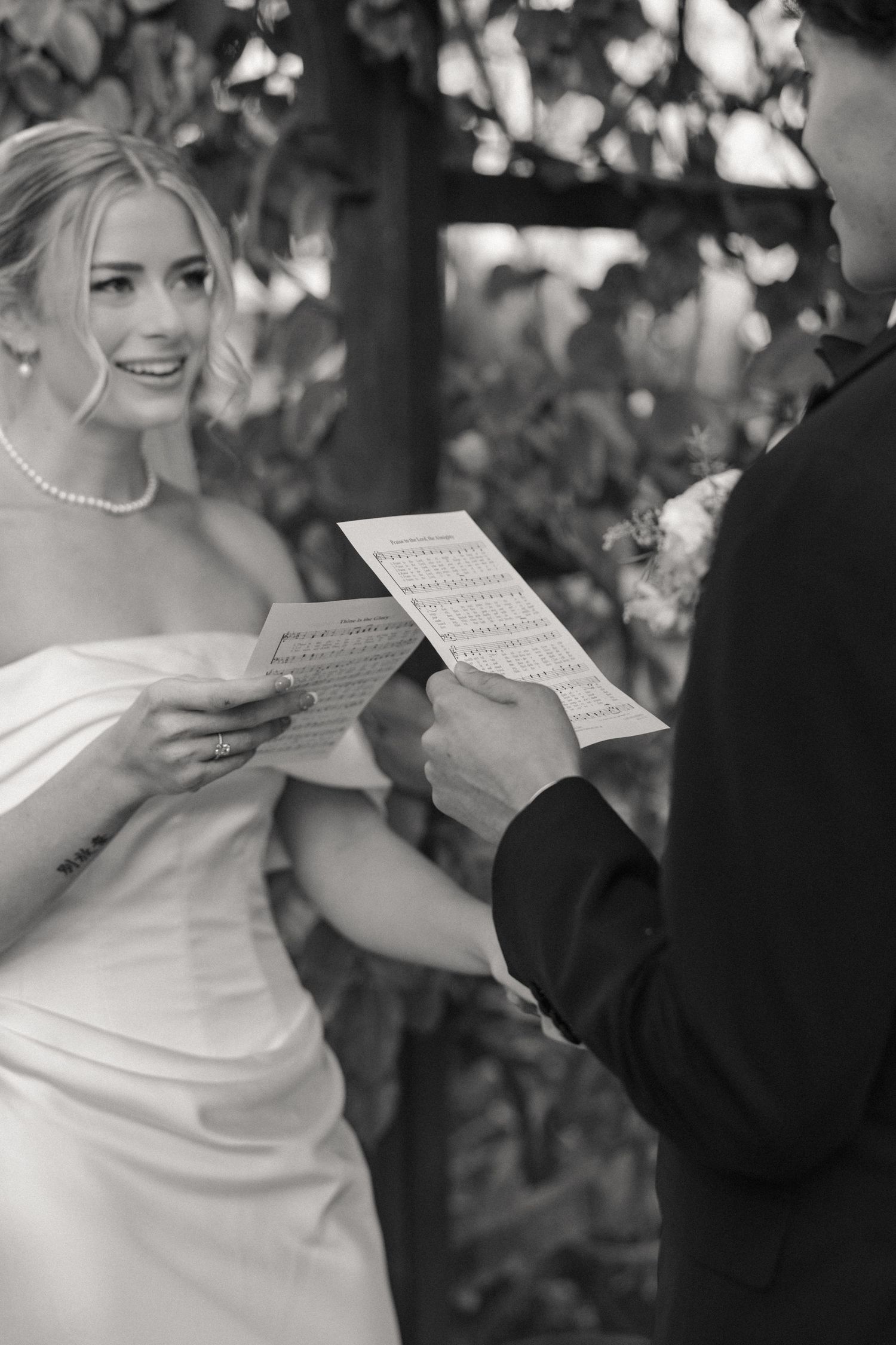 Couple exchanging vows and reading from papers during an outdoor wedding ceremony.